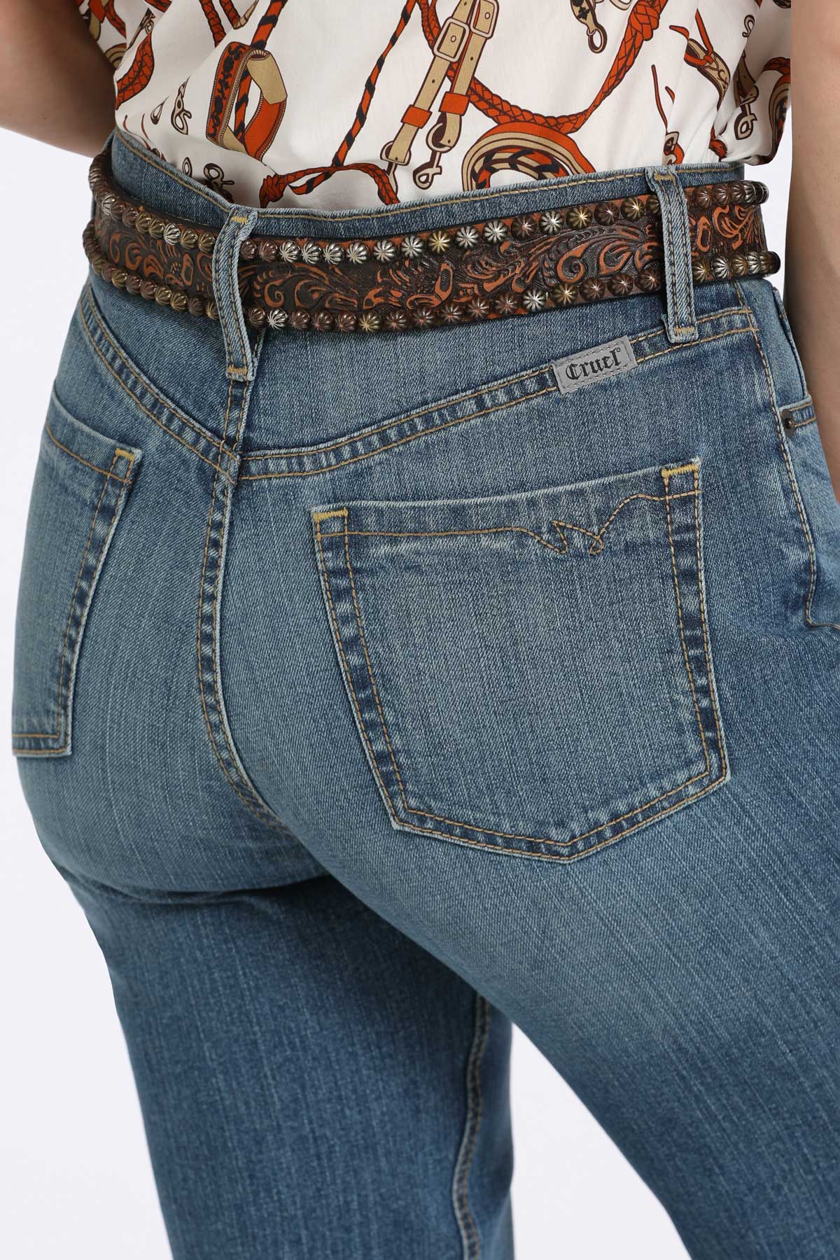 Close-up of blue jeans with a decorative belt on a white background