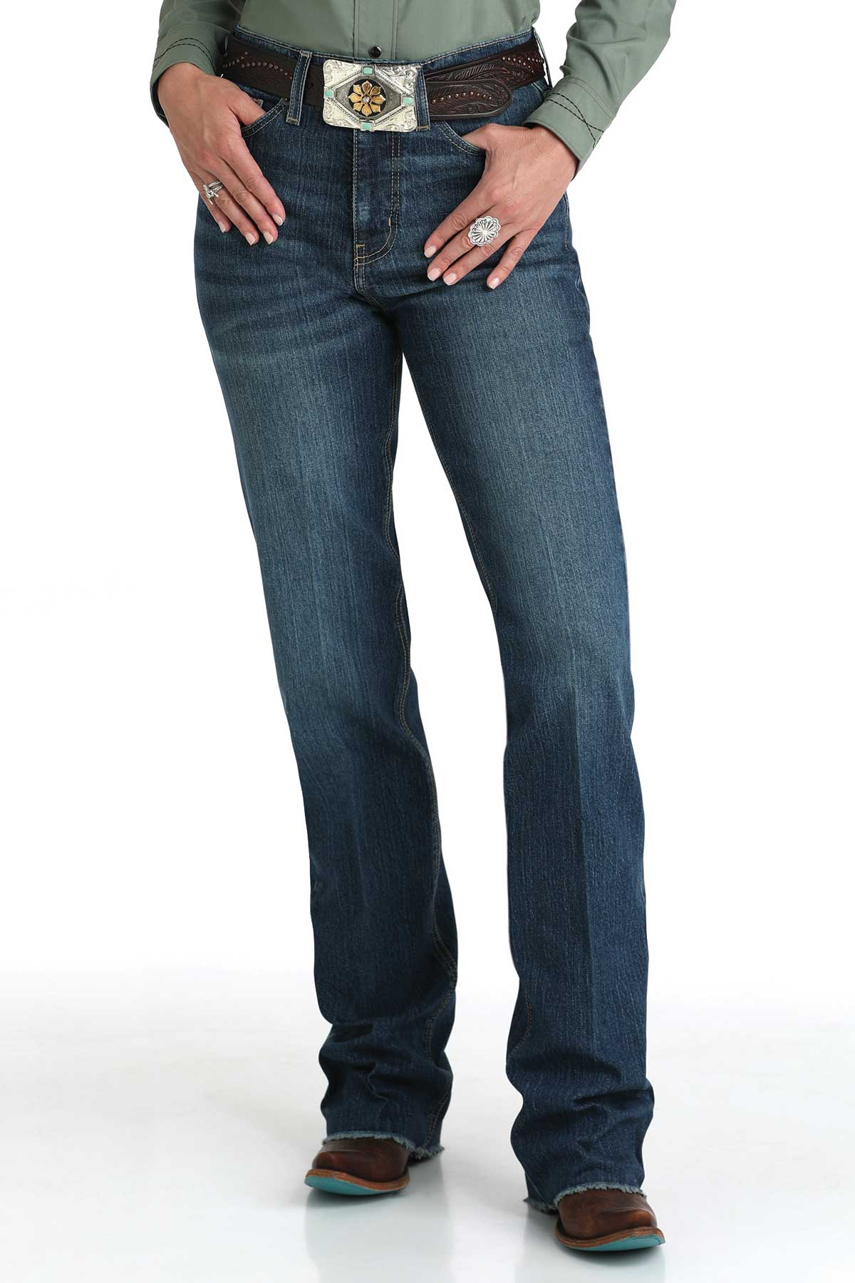 Woman wearing dark wash bootcut jeans with a decorative belt buckle and brown boots