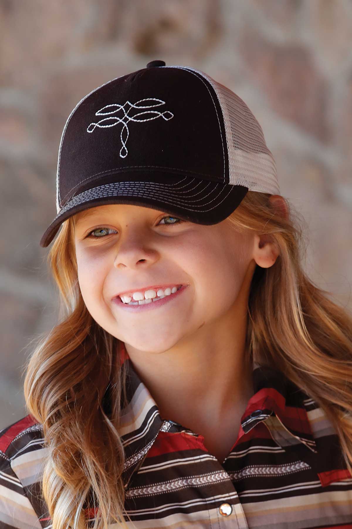 Close-up of a young girl wearing a black and white hat with a collared button-down shirt
