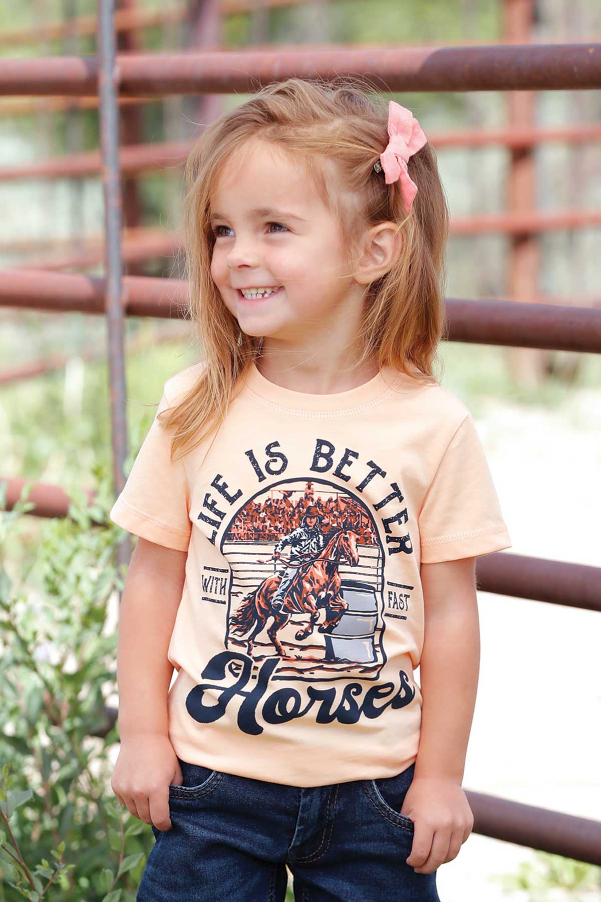 Young girl wearing a t-shirt with a horse graphic and text, standing outdoors.