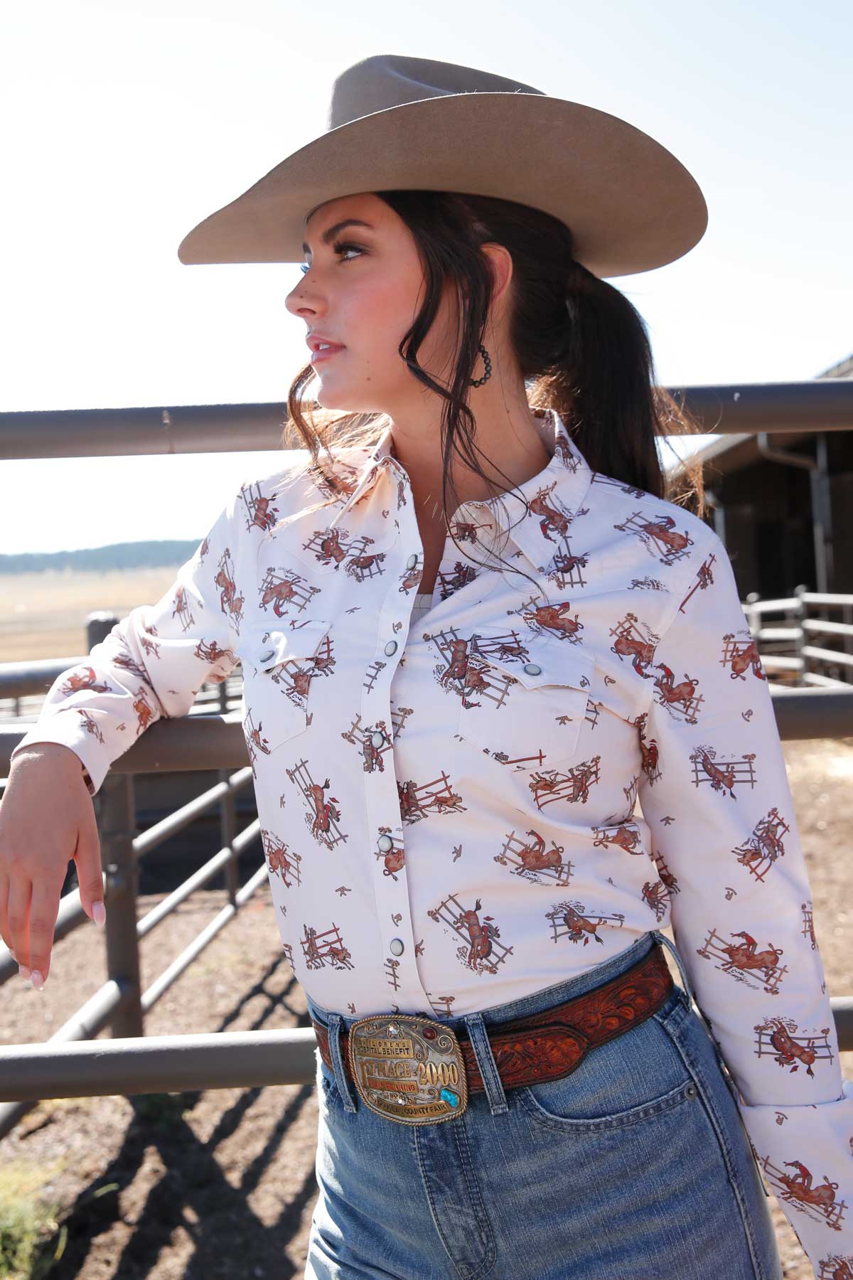 Woman wearing a cowboy hat and patterned shirt in an outdoor setting