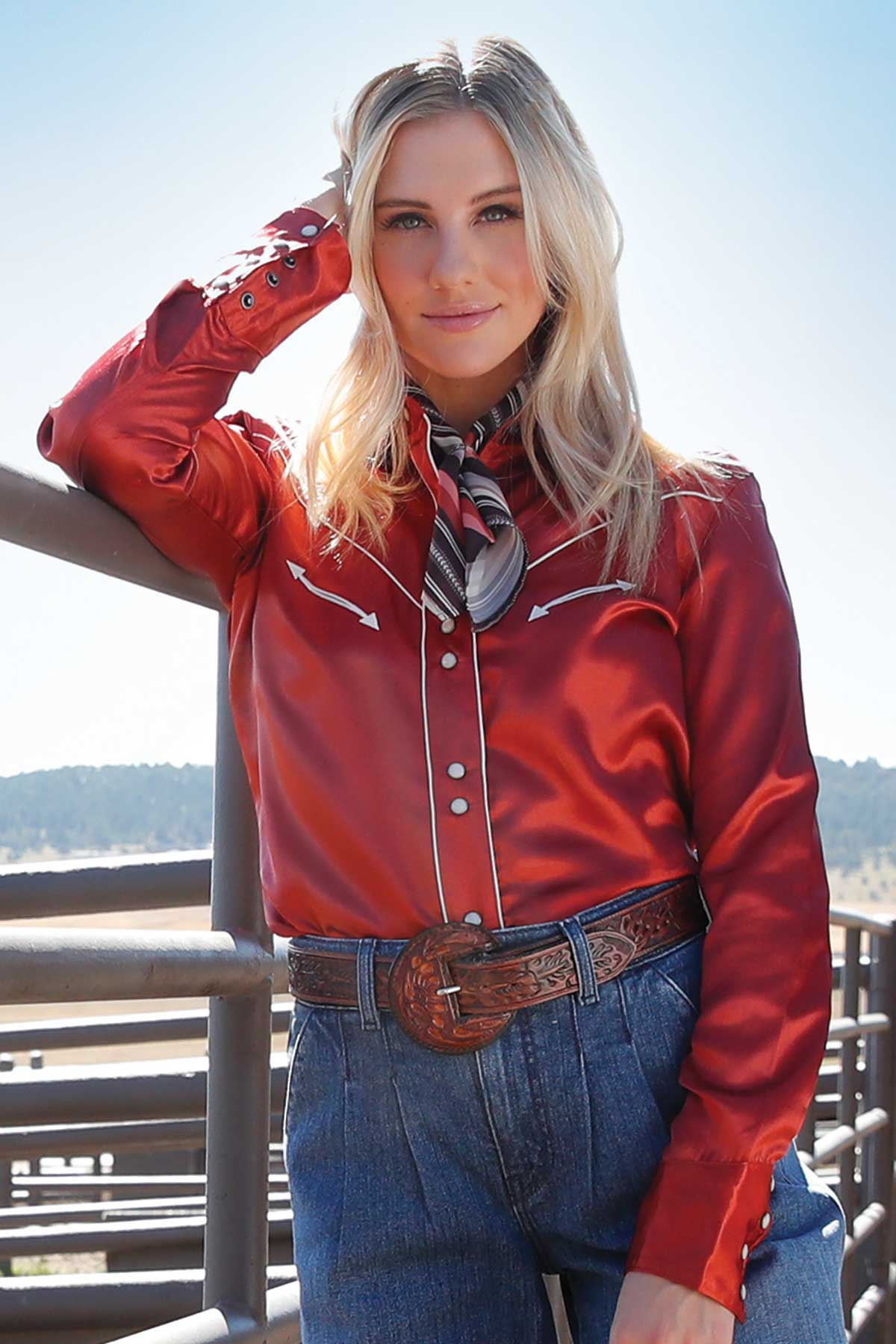 Woman standing outside wearing a red silk shirt and jeans