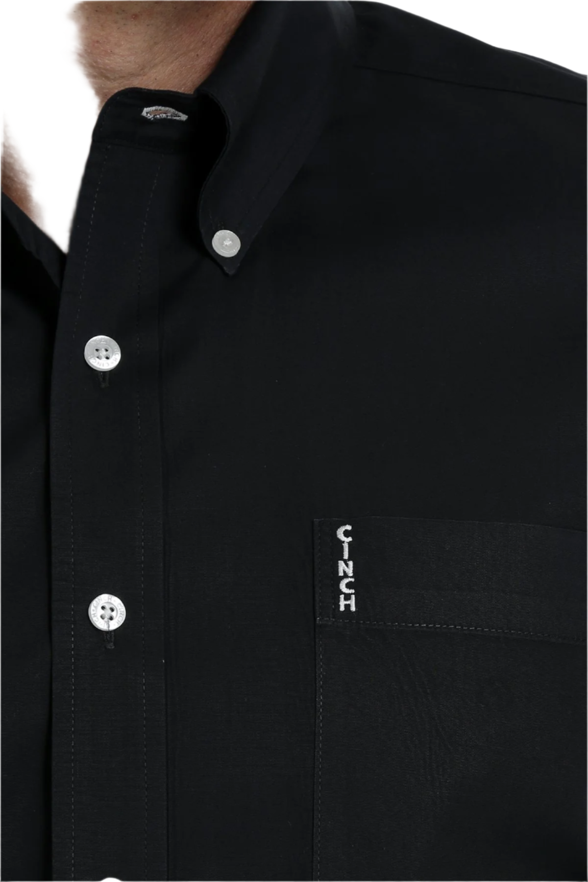 Close-up of a man wearing a long sleeve black button-down shirt with a Cinch logo.