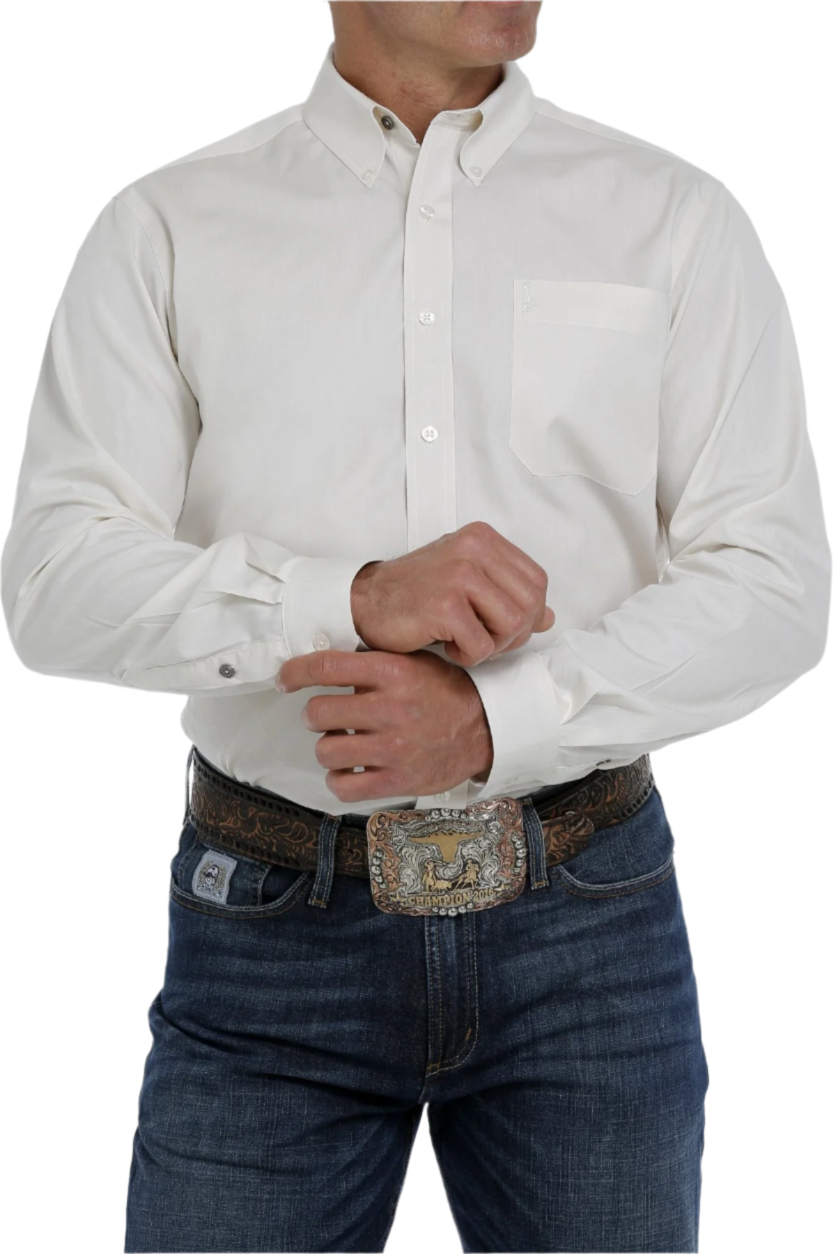 A man wearing a long sleeve cream-colored button-down shirt and blue jeans. The shirt has a single chest pocket and white buttons.