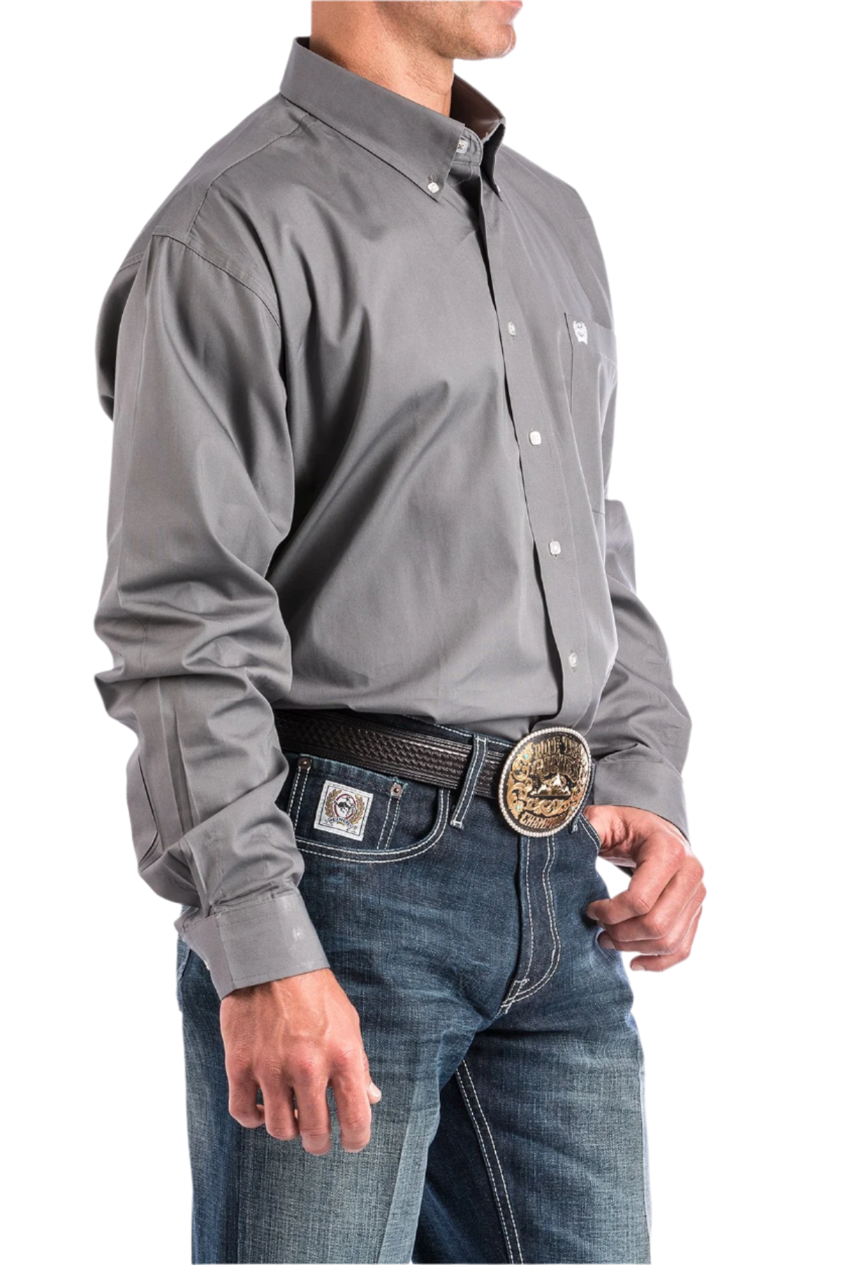 A man wearing a long-sleeve grey button-down shirt and blue jeans, with a belt and buckle visible.