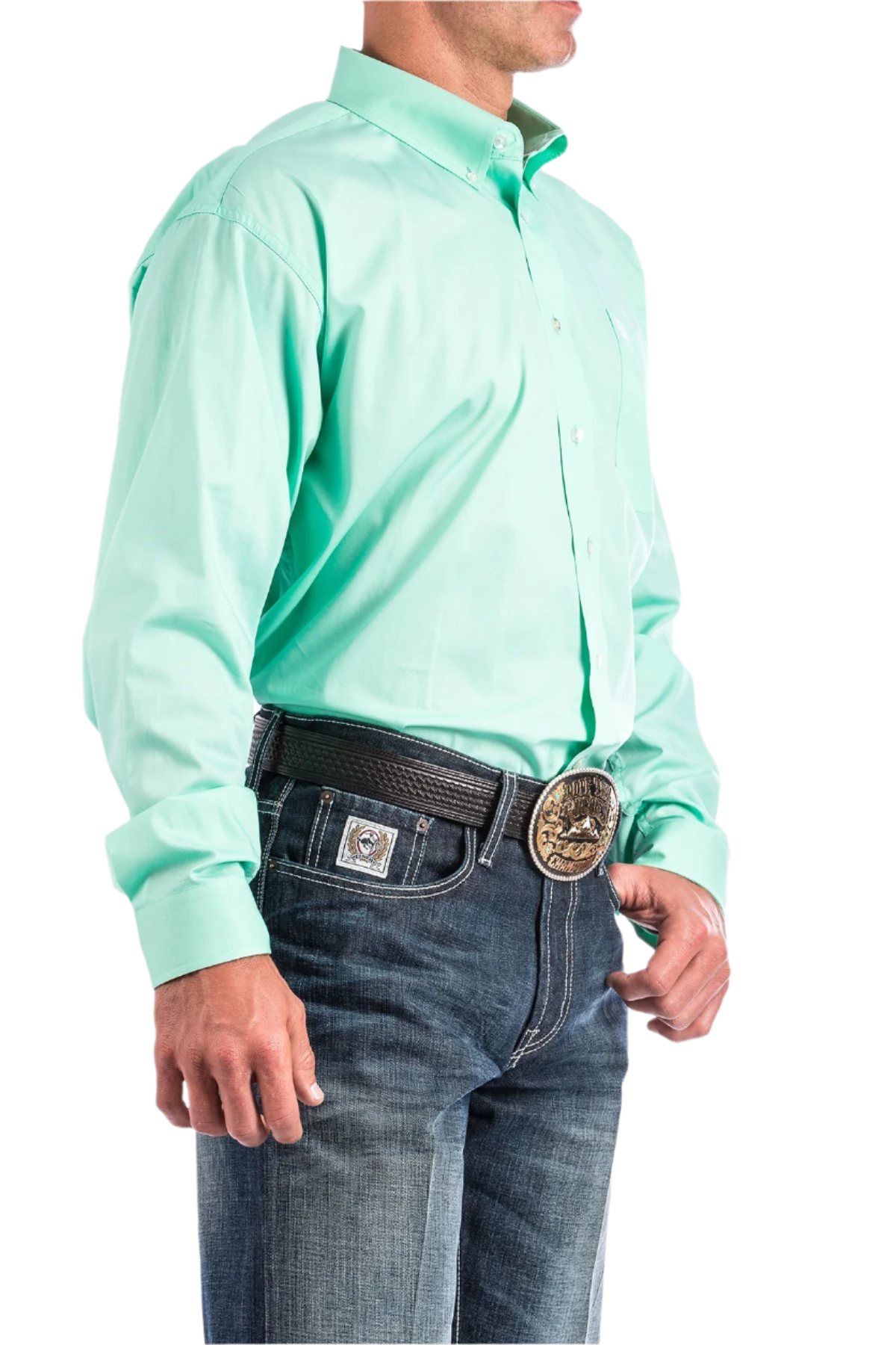 A man wearing a long-sleeve mint green Western shirt with a button-down collar, paired with blue jeans and a belt with a decorative buckle.