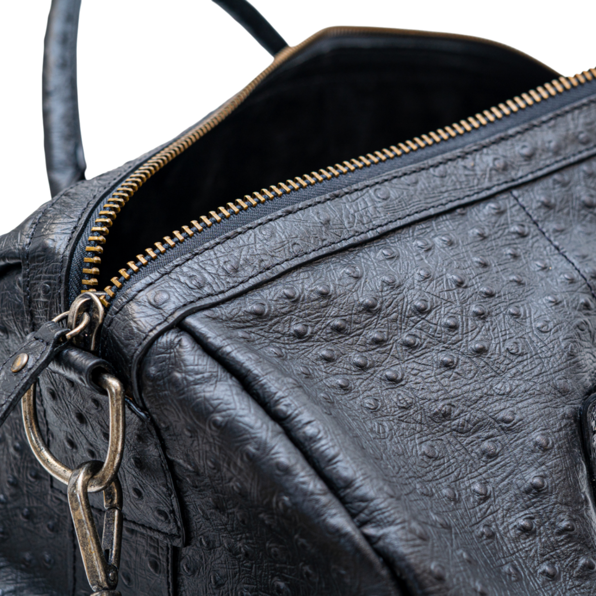 Close-up of a black textured leather bag with gold zipper and hardware.