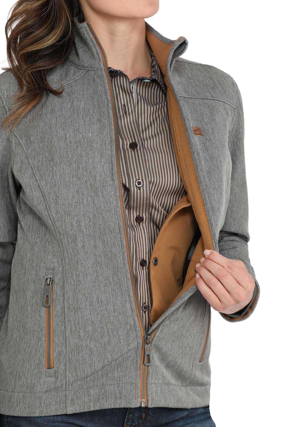 A woman unzips a light gray jacket to show the tan interior pocket, revealing a striped button-down shirt underneath.