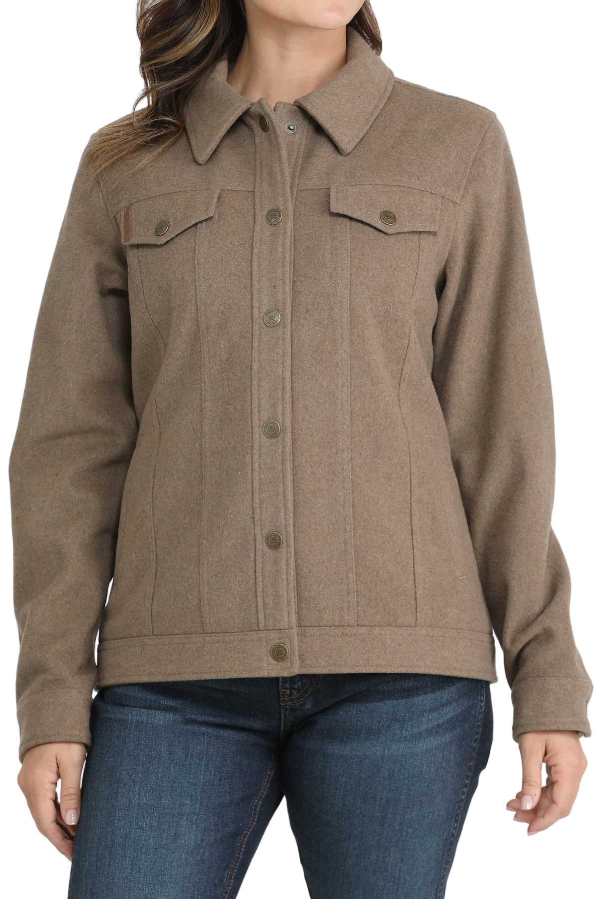 A woman wearing a taupe button-up jacket with flap chest pockets and long sleeves, paired with blue jeans