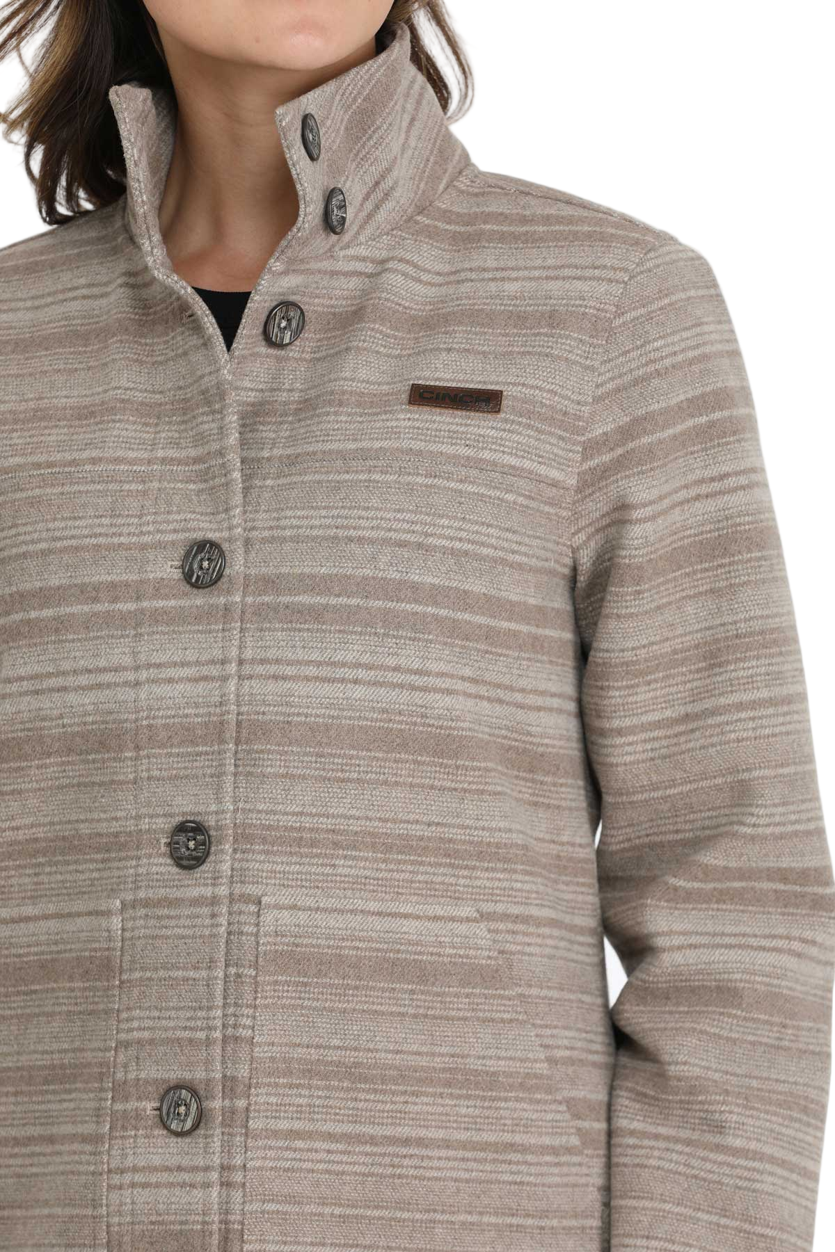 Close-up of a woman wearing a beige patterned button-up jacket with a high collar
