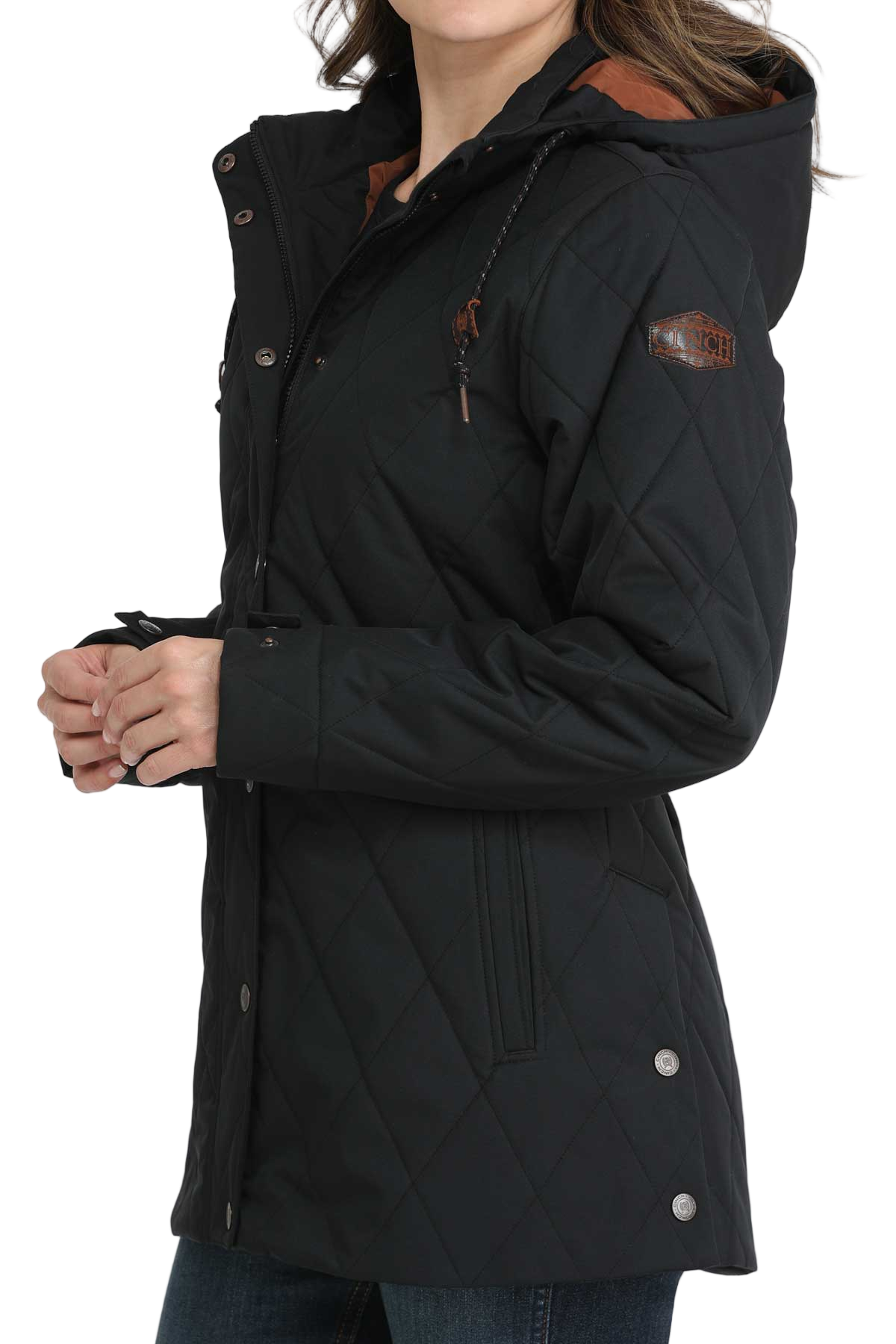 Woman wearing a long black quilted jacket with a hood and jeans