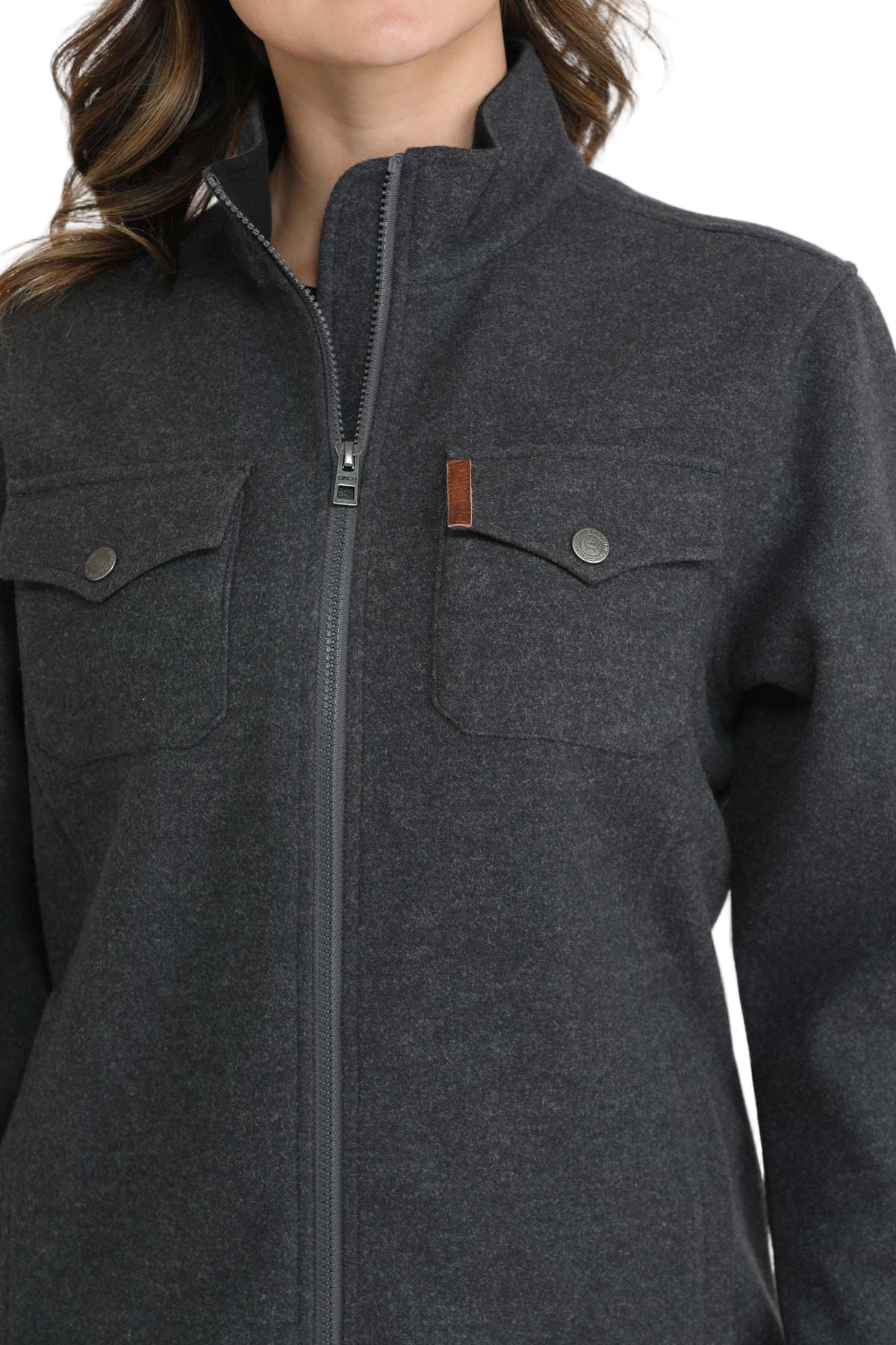 Woman wearing a dark gray zip-up jacket with flap chest pockets, a high collar and a simple, casual design