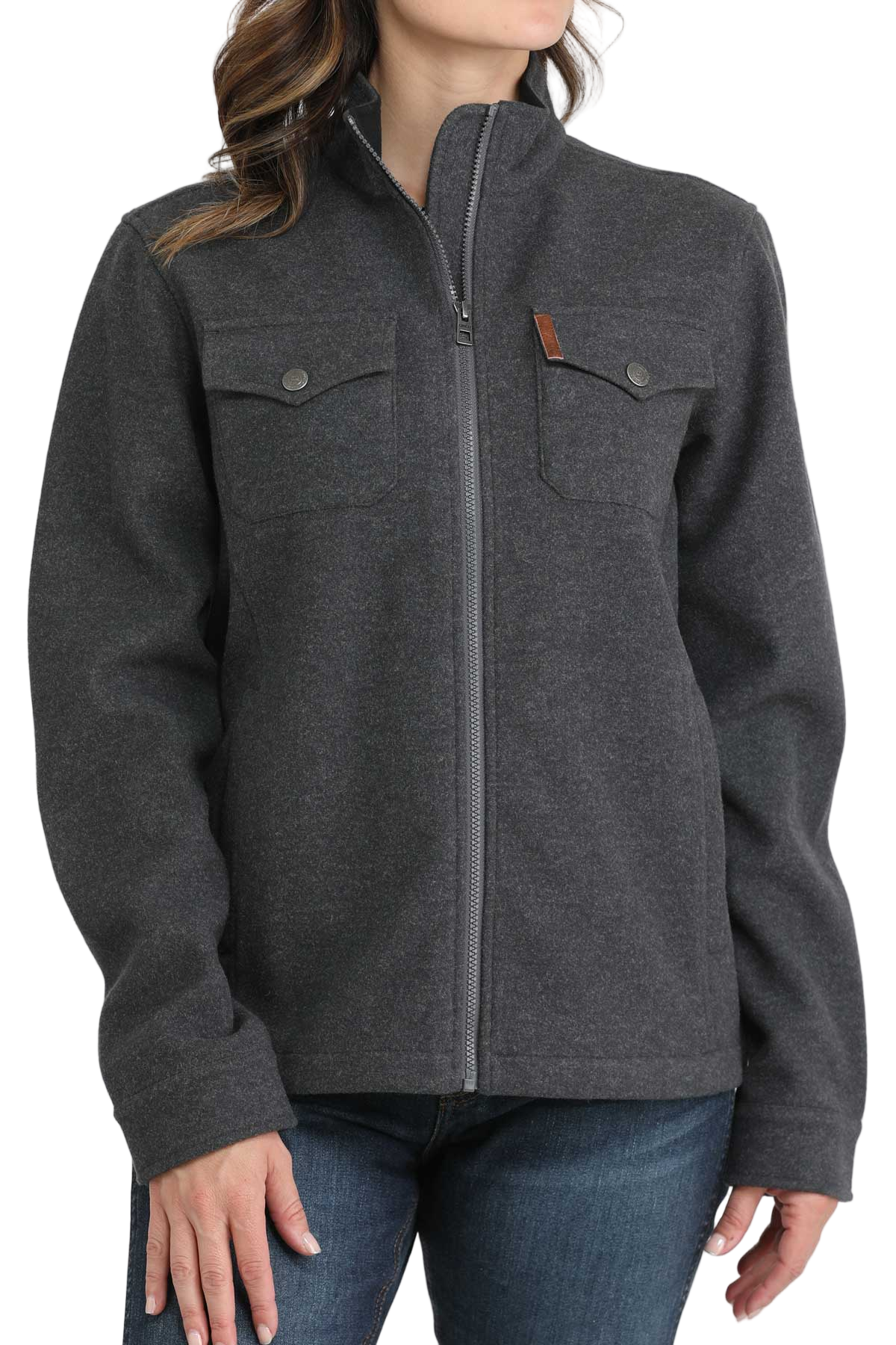 Woman wearing a dark gray zip-up jacket with flap chest pockets and side pockets, paired with blue jeans. The jacket has a high collar and a simple, casual design