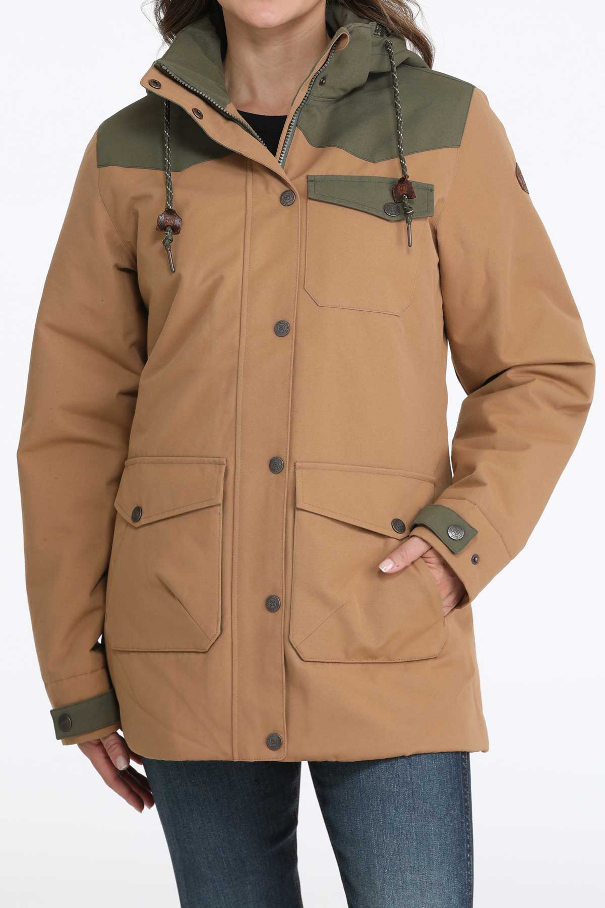 Woman wearing a brown jacket with green accents and jeans
