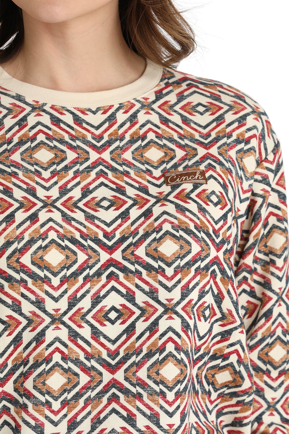 Person wearing a patterned sweater with a visible brand logo.