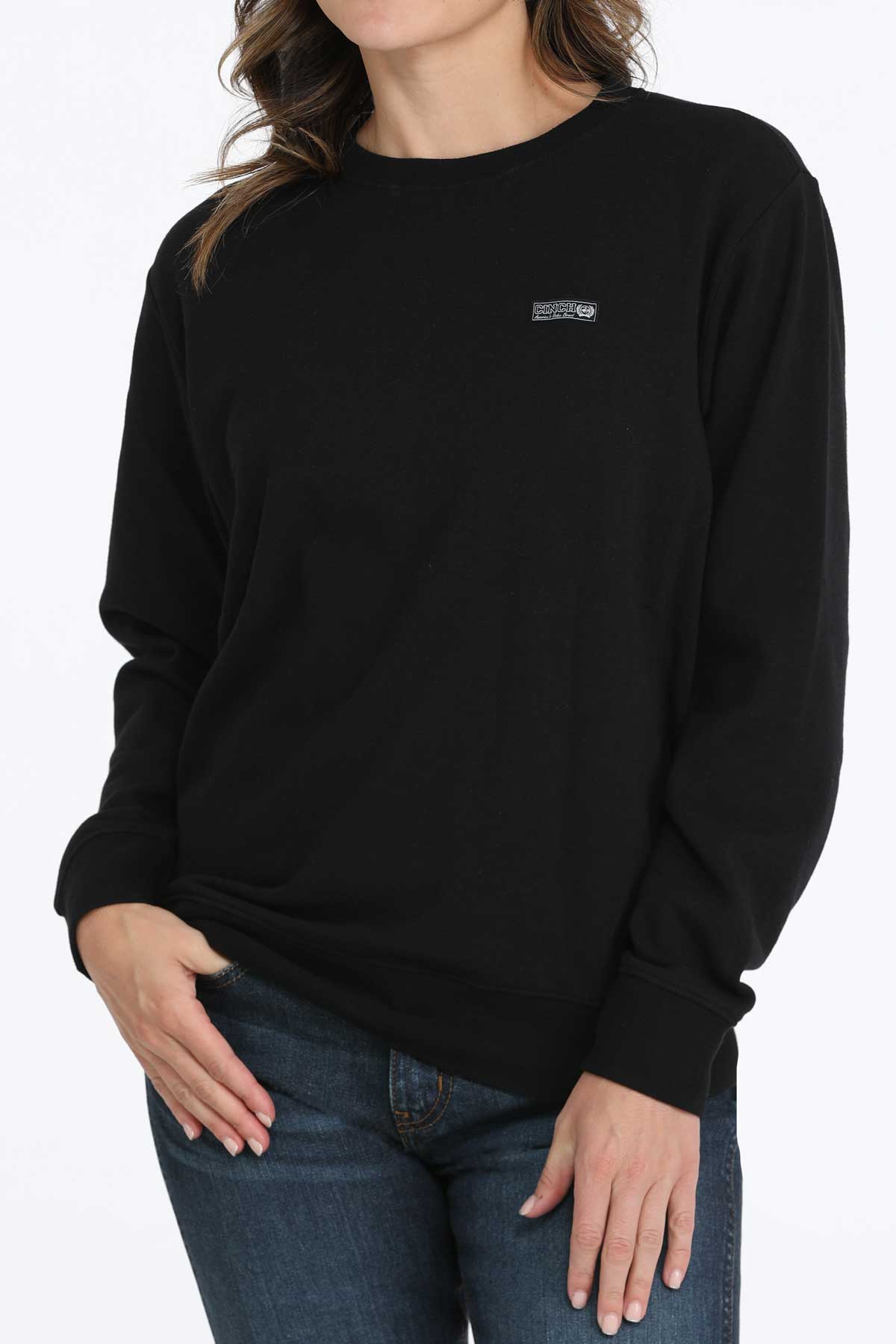 Person wearing a black sweatshirt with a small logo on a white background