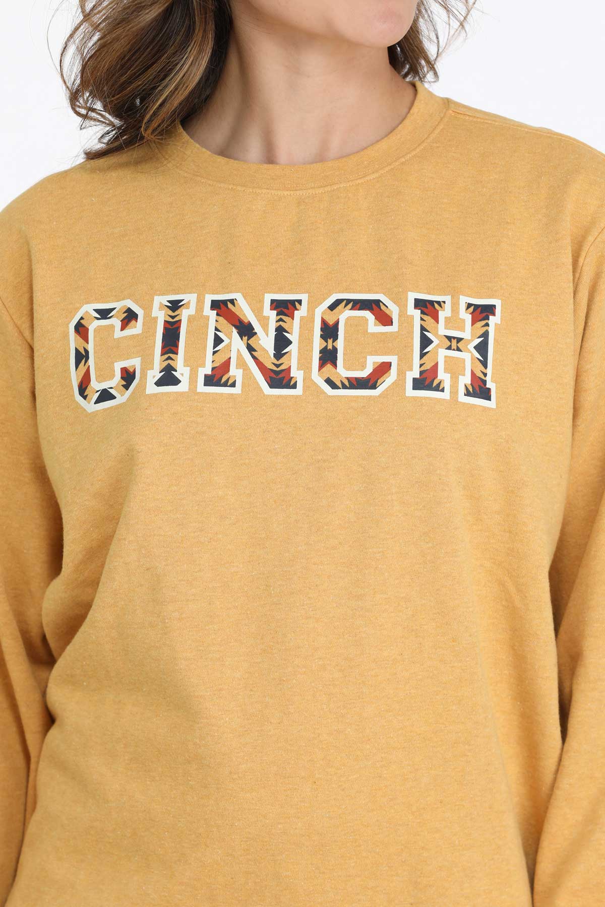 Close-up of patterned CINCH logo across chest of gold ladies’ sweatshirt