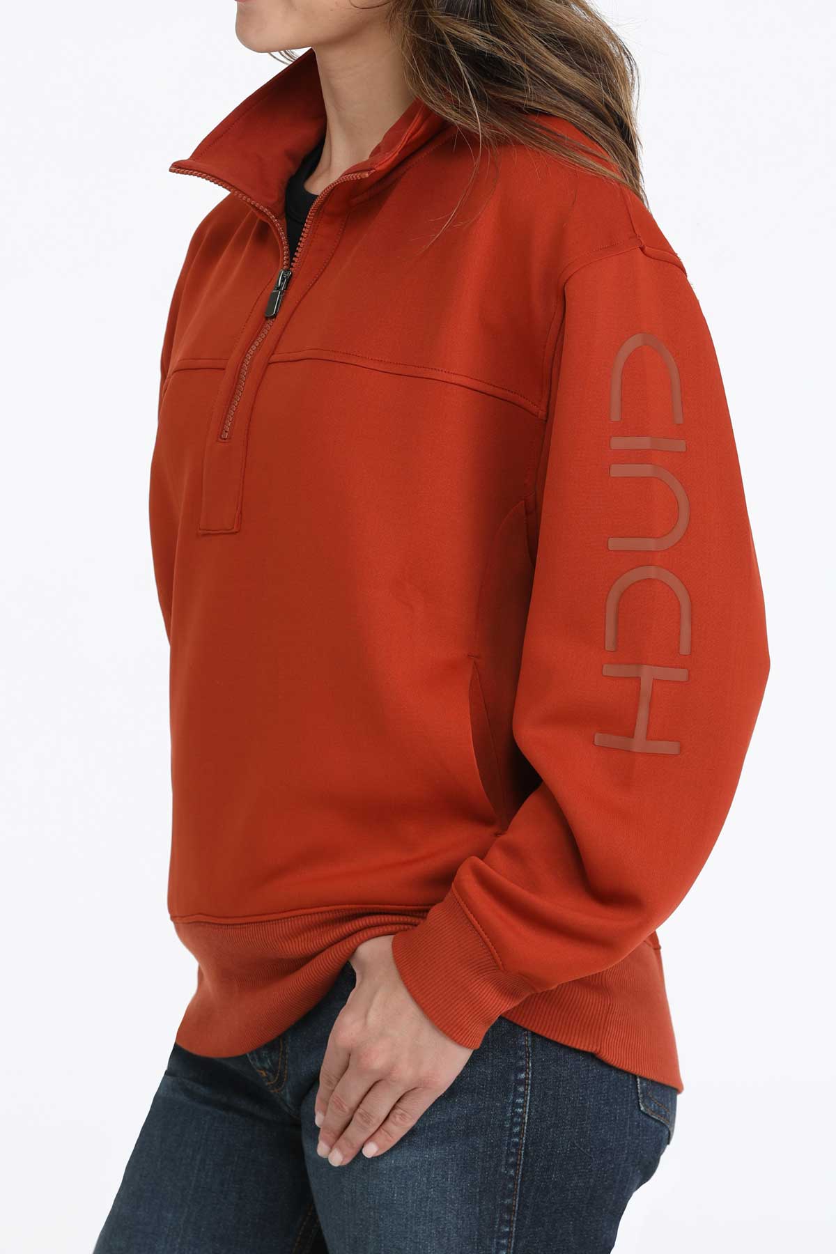 Woman wearing a Cinch ladies’ red quarter-zip sweatshirt with jeans on a white background