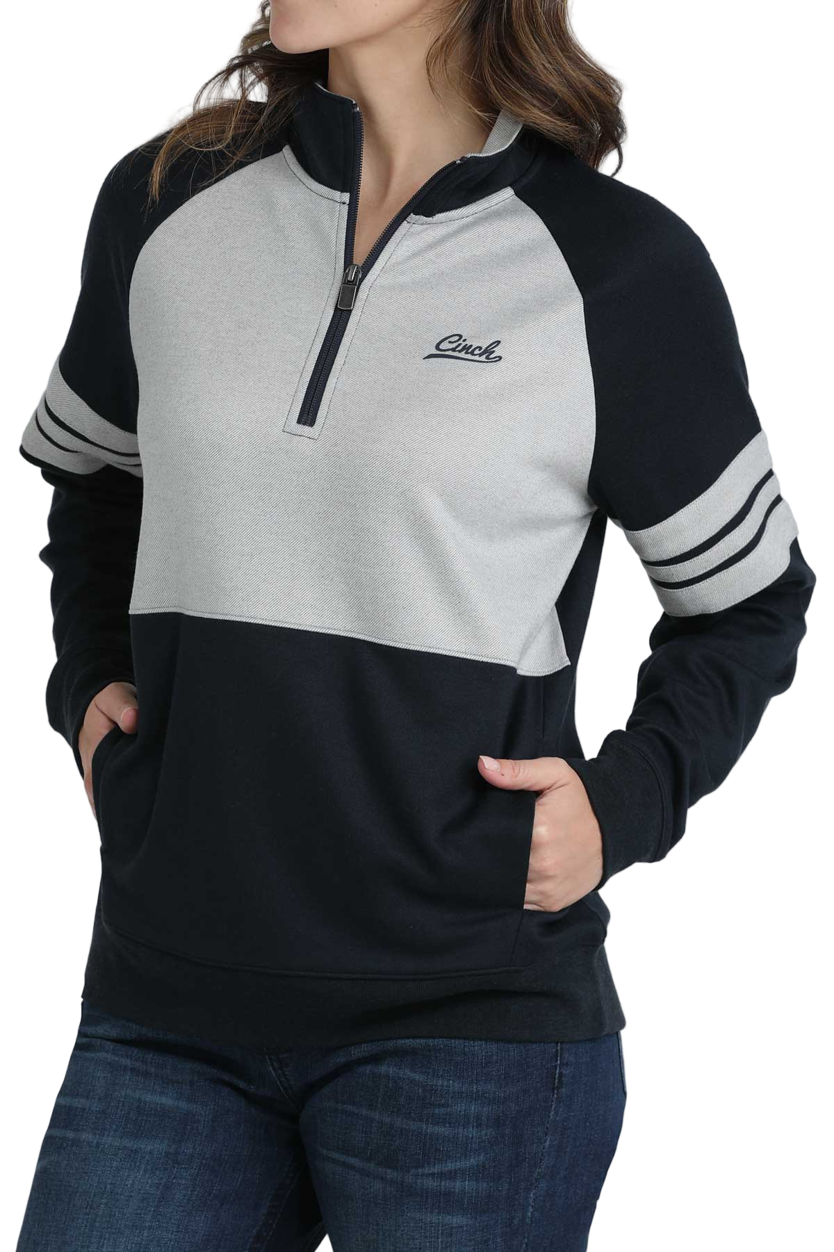 Woman wearing a black and heather-gray quarter-zip pullover with striped sleeves and dark jeans
