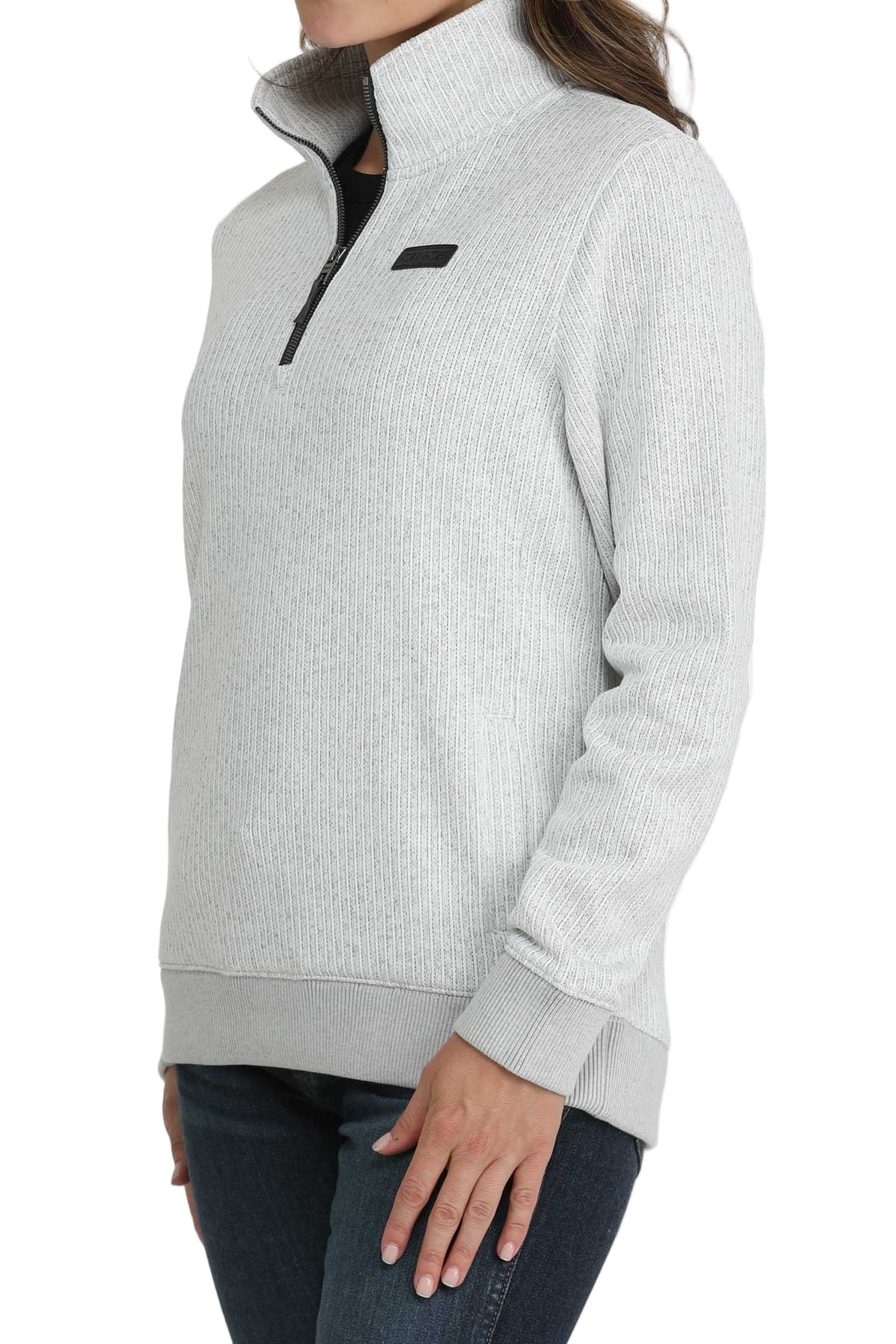 Woman wearing a light gray quarter-zip pullover with a high collar, ribbed cuffs and hem, paired with dark-wash jeans