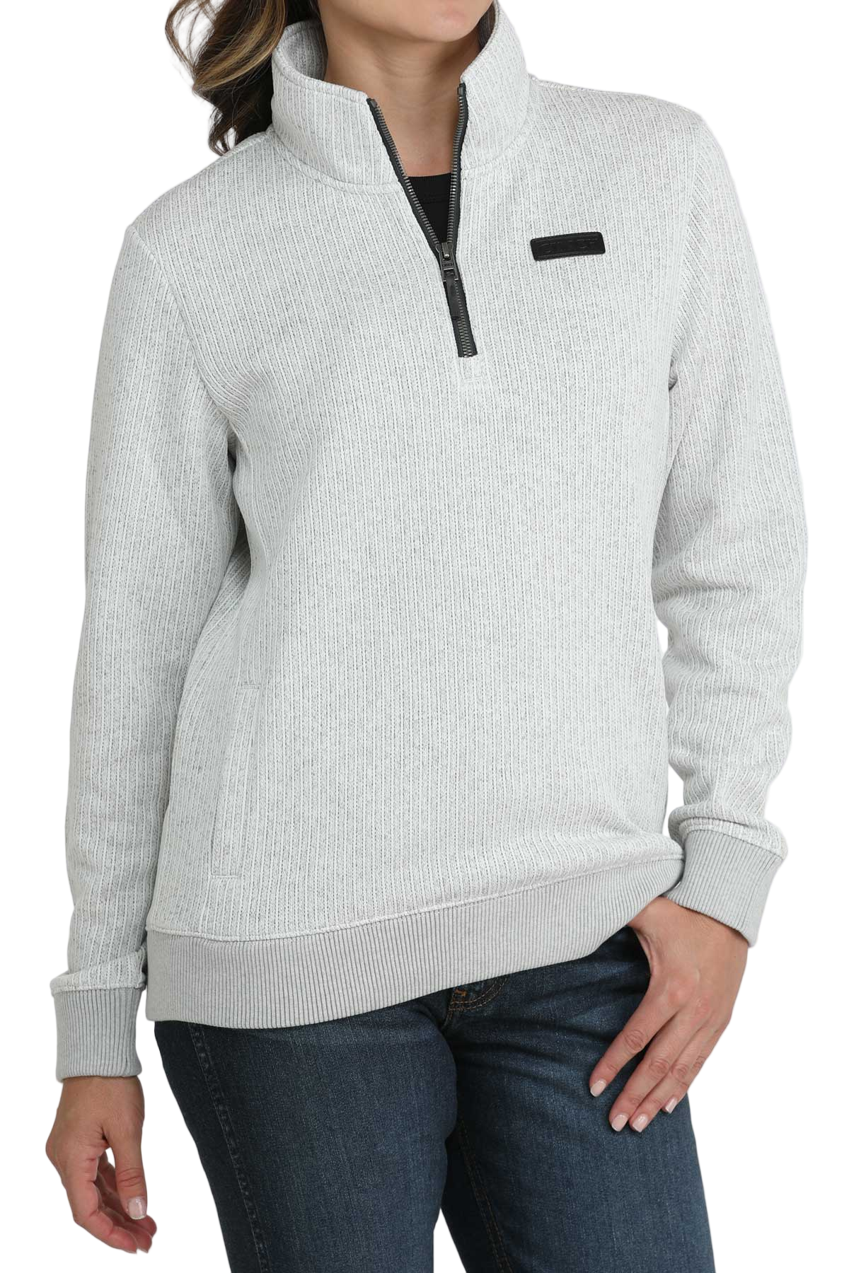 Woman wearing a light gray quarter-zip pullover with a high collar, ribbed cuffs and hem, paired with dark-wash jeans