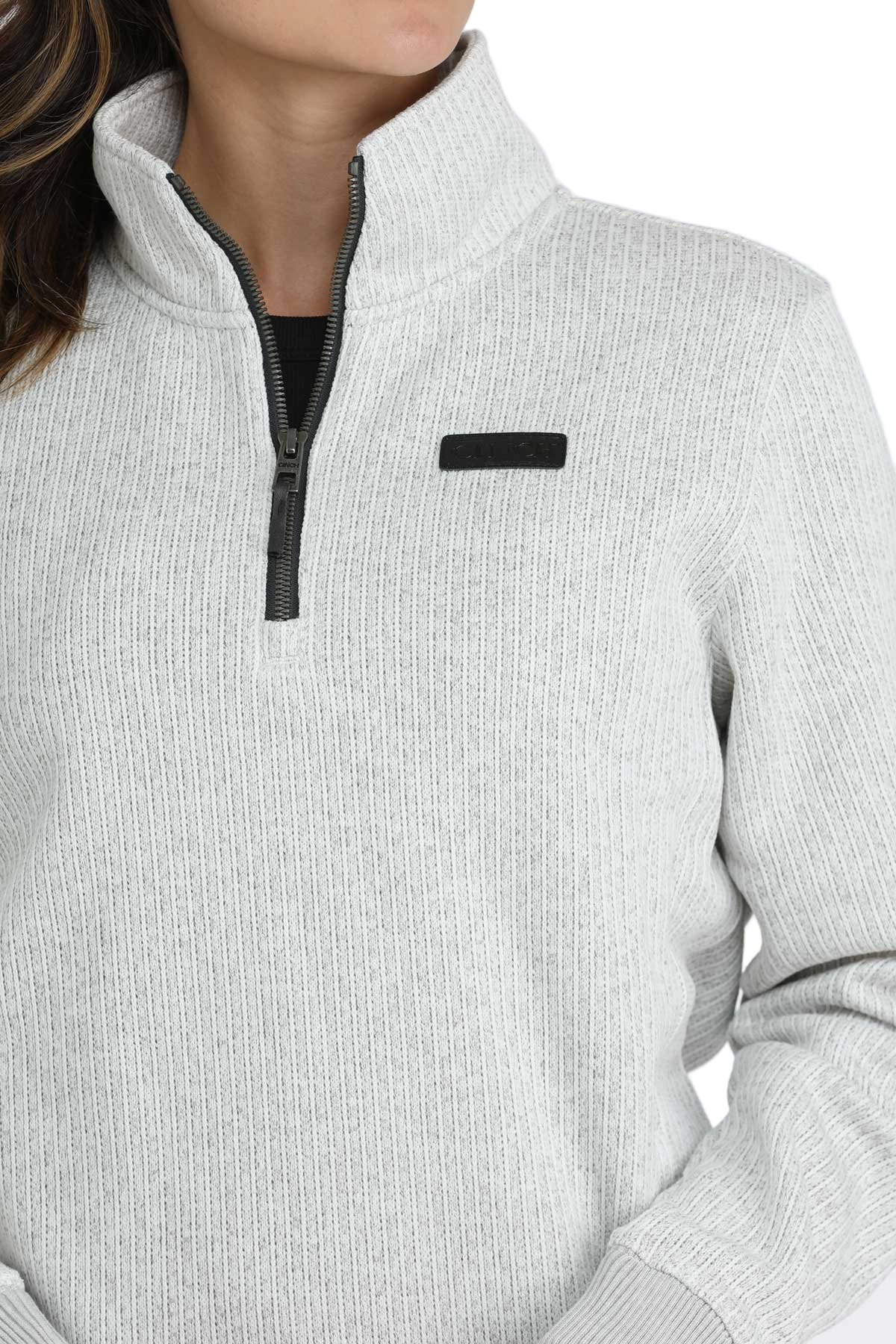 Close-up of a woman wearing a light gray quarter-zip pullover with a high collar