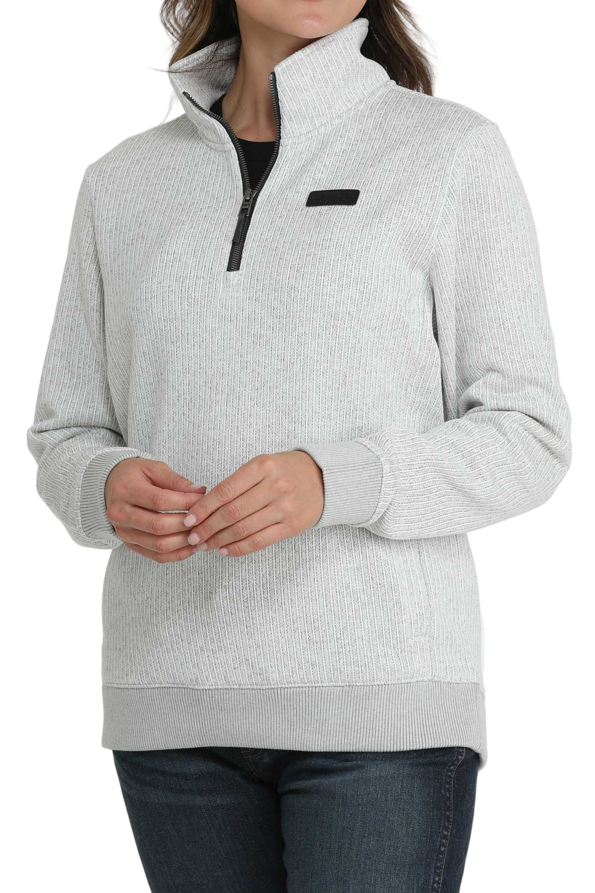 Woman wearing a light gray quarter-zip pullover with a high collar, ribbed cuffs and hem, paired with dark-wash jeans