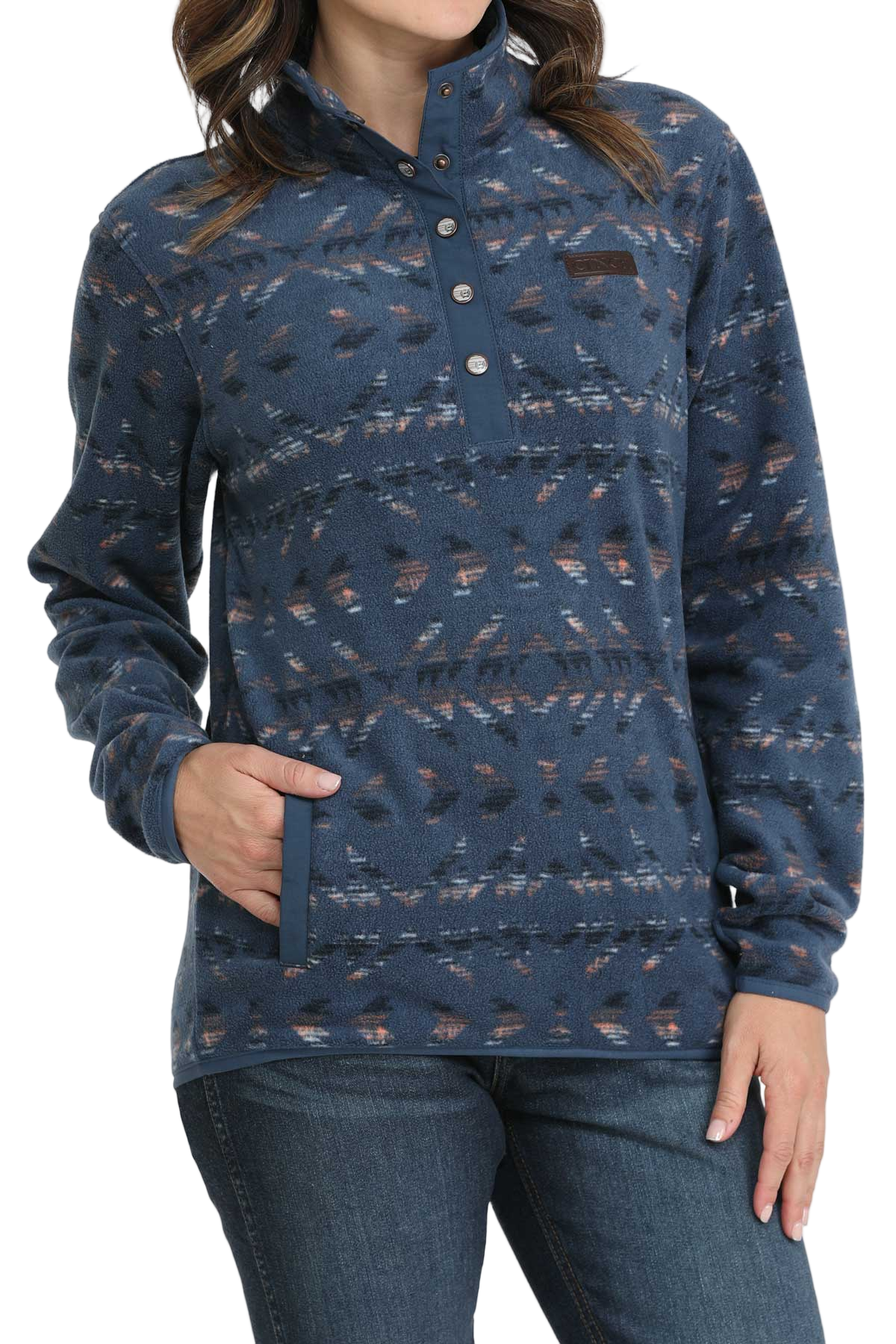 Woman wearing a blue patterned fleece pullover with a snap-up collar and front pocket, paired with dark denim jeans