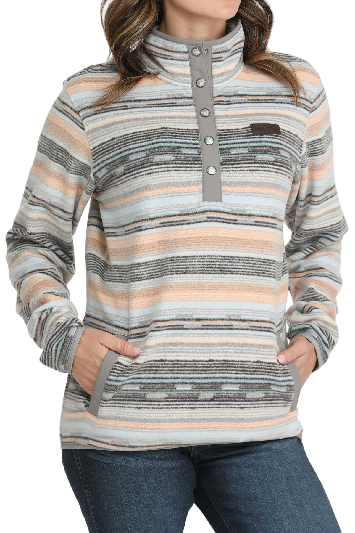 Woman wearing a striped fleece pullover with a snap-up mock neck and front pockets, paired with dark denim jeans