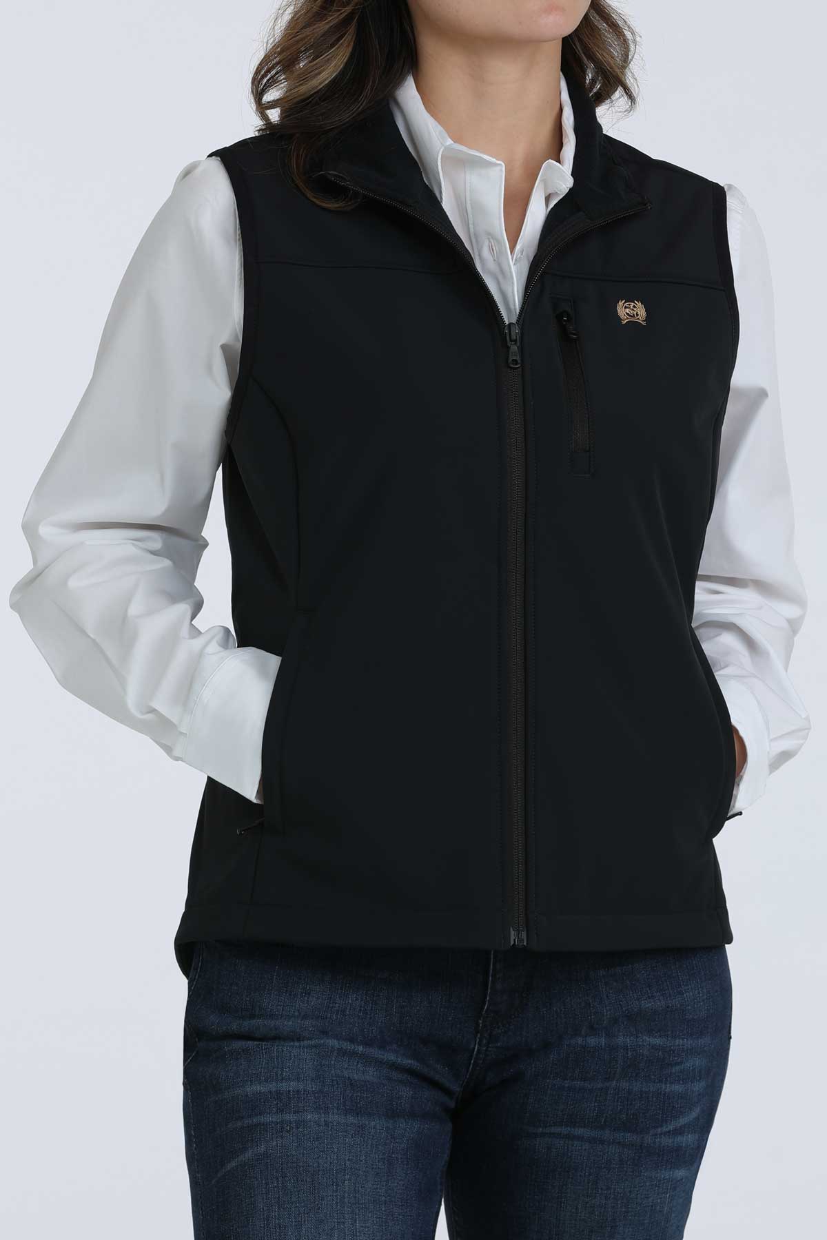 Woman wearing a black vest with a white undershirt and jeans