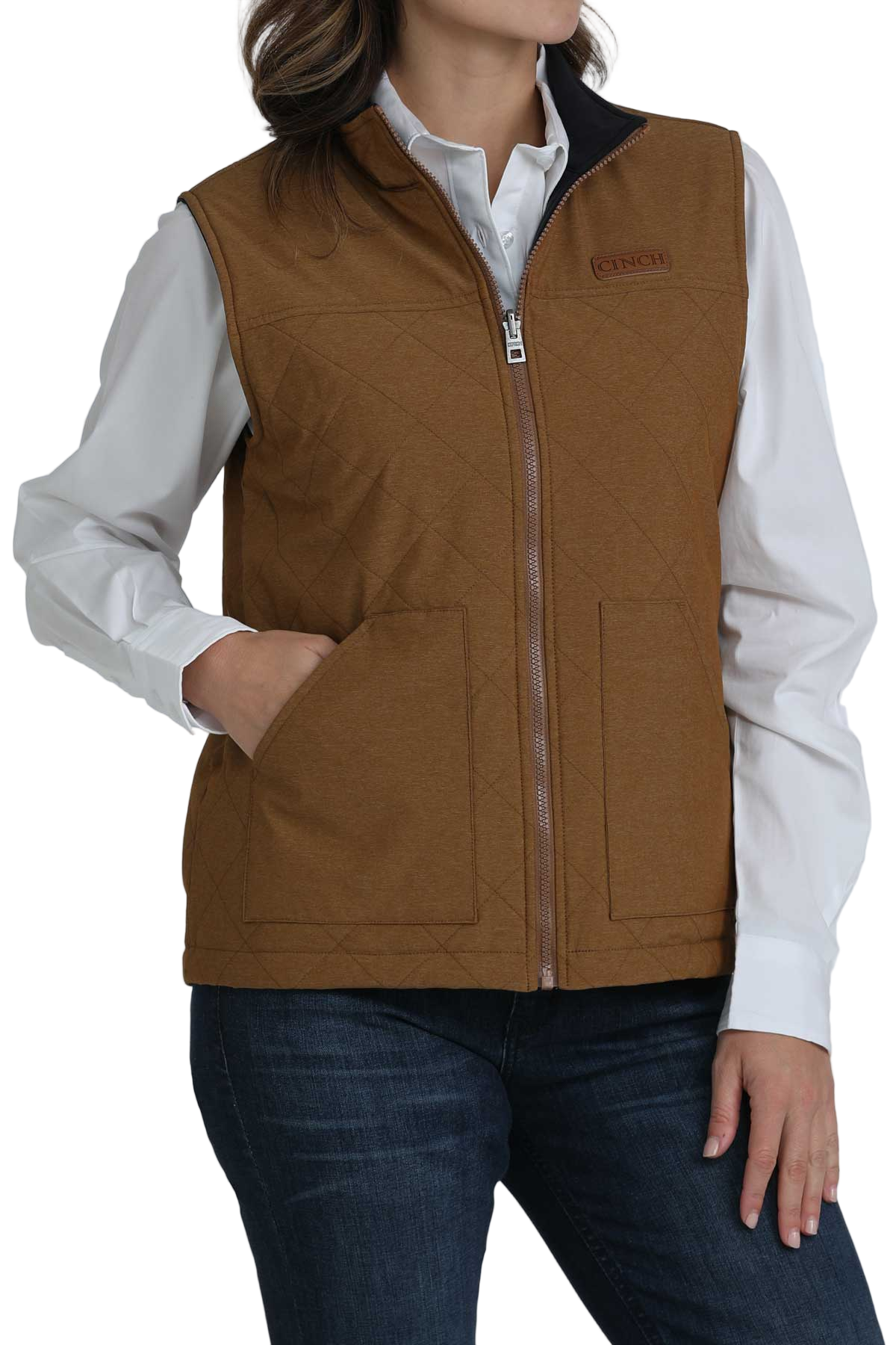 Woman wearing a brown quilted vest over a white button-up shirt and dark jeans