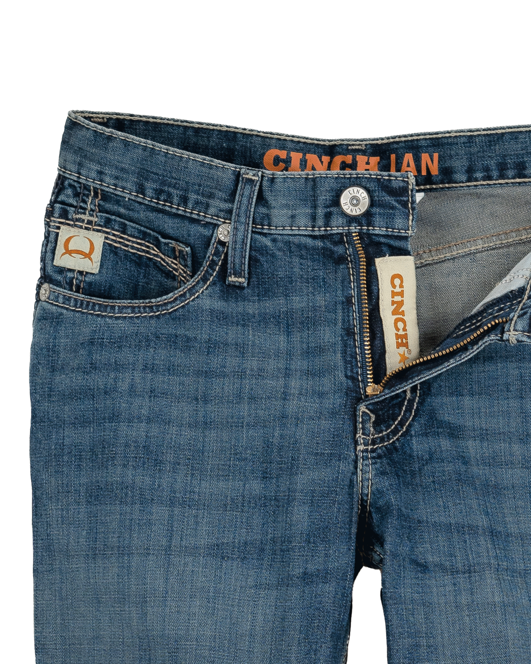 Close-up of blue jeans with Cinch brand labels on a white background