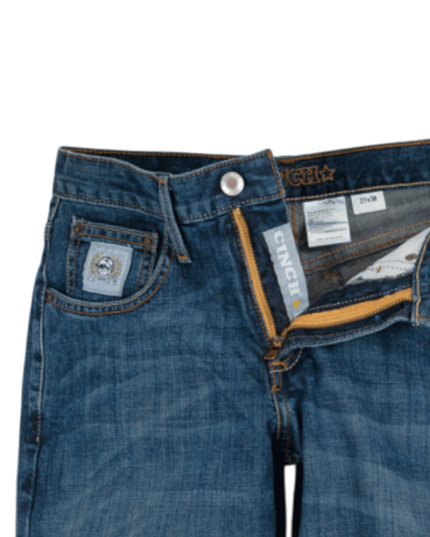Close-up of the front of blue denim jeans with light fading, featuring a coin pocket with a small embroidered patch, belt loops, and a button closure with a zipper fly. The waistband has 'CINCH' stitched in gold thread
