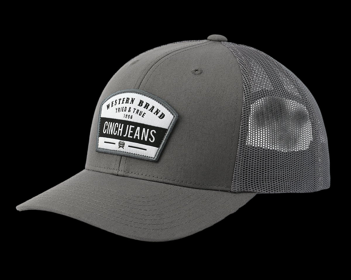 Angled front view of gray Cinch trucker cap with bold CINCH Jeans patch logo and mesh back, displayed on a white background