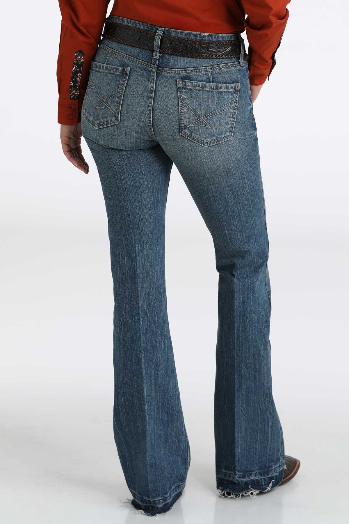 Back-view of women's medium washed blue jeans paired with a red shirt, a belt and boots