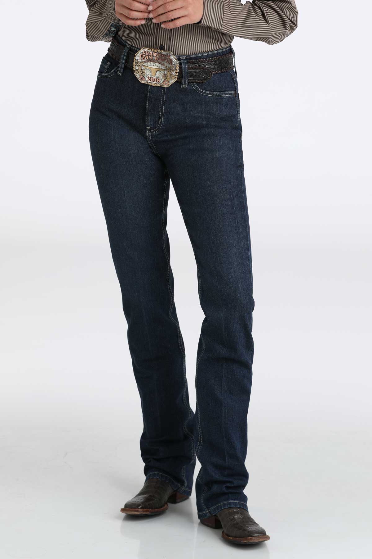 Person wearing dark wash bootcut jeans with a large belt buckle and cowboy boots