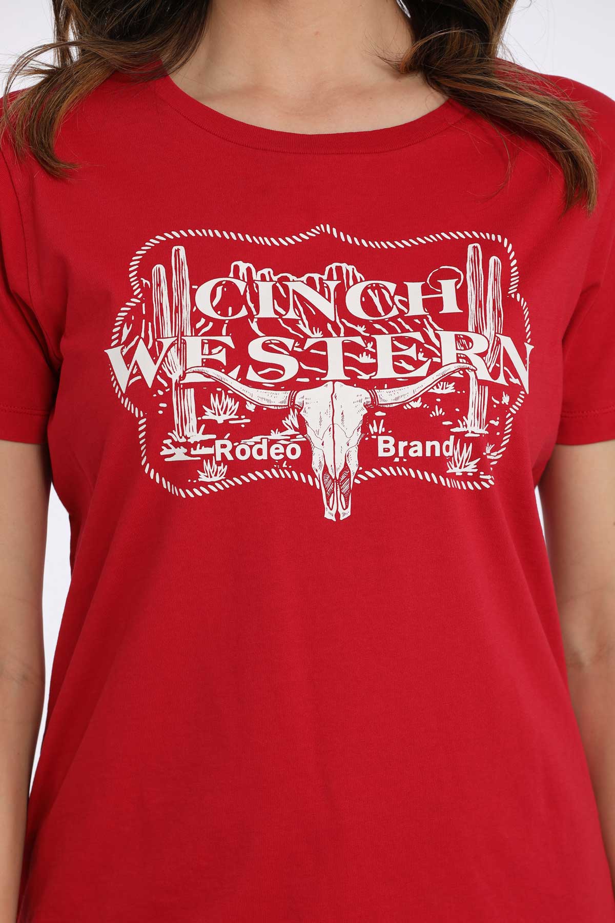 Close-up of a woman wearing a red t-shirt with a western graphic on a white background