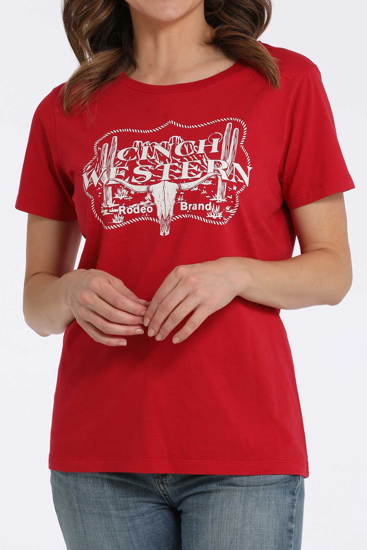 Woman wearing a red t-shirt with a western graphic and jeans on a white background