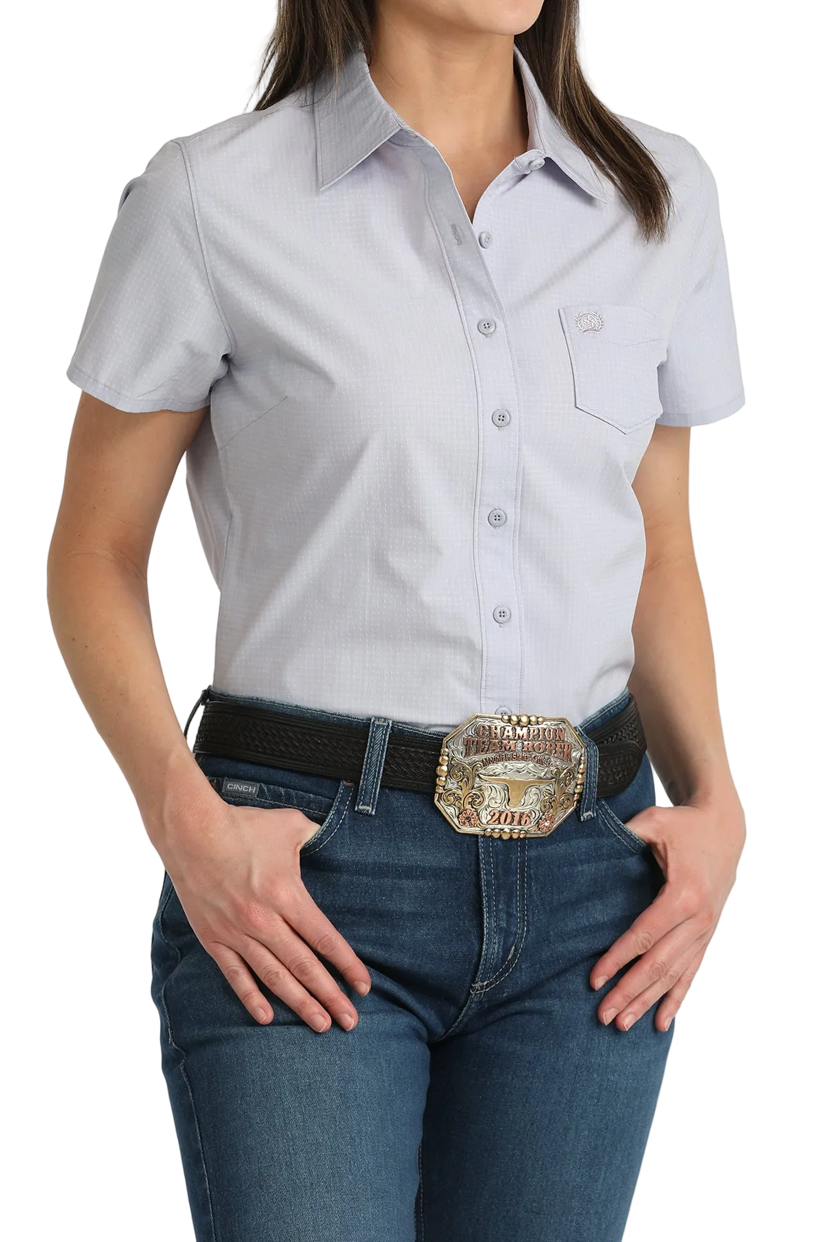 Woman wearing a light gray short-sleeve shirt and blue jeans with a belt and buckle.