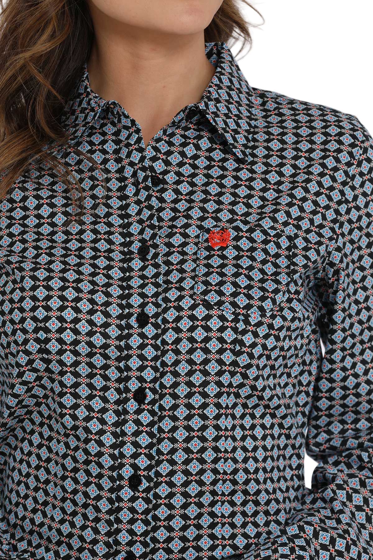 Woman wearing a patterned button-down shirt with a small red logo on the chest
