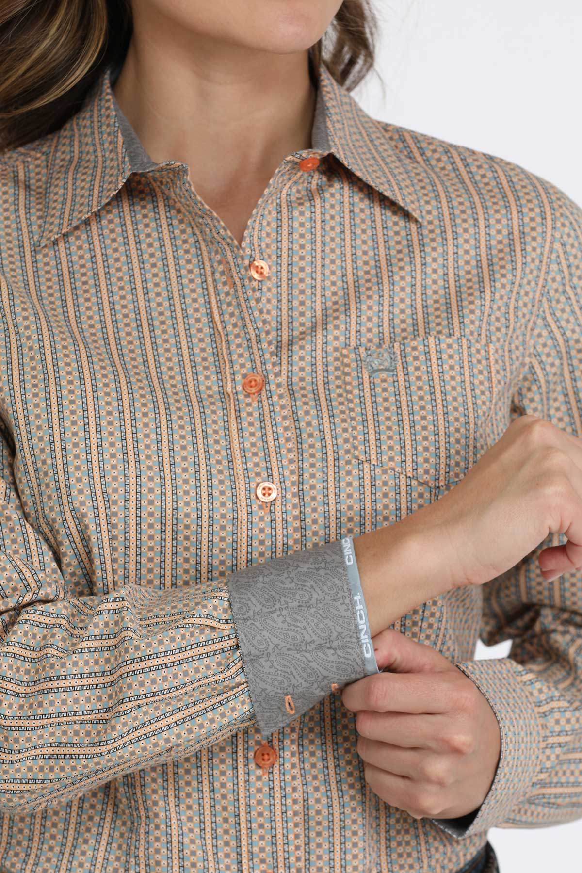 Close-up of a woman wearing a brown long sleeve button-down with contrasting cuffs