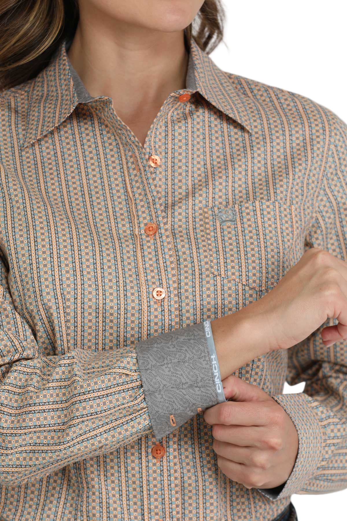Close-up of a woman wearing a brown striped button-down shirt with contrast cuffs