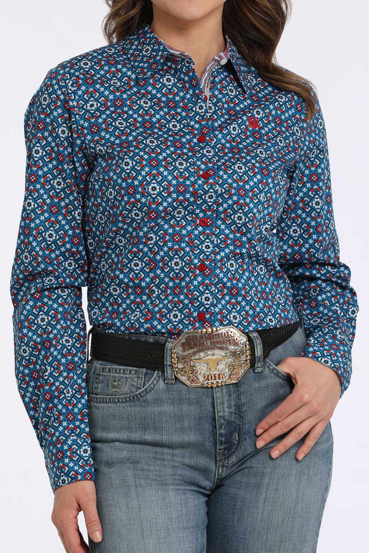 Woman wearing a blue long sleeve button-down with a geometric pattern, paired with jeans and a belt