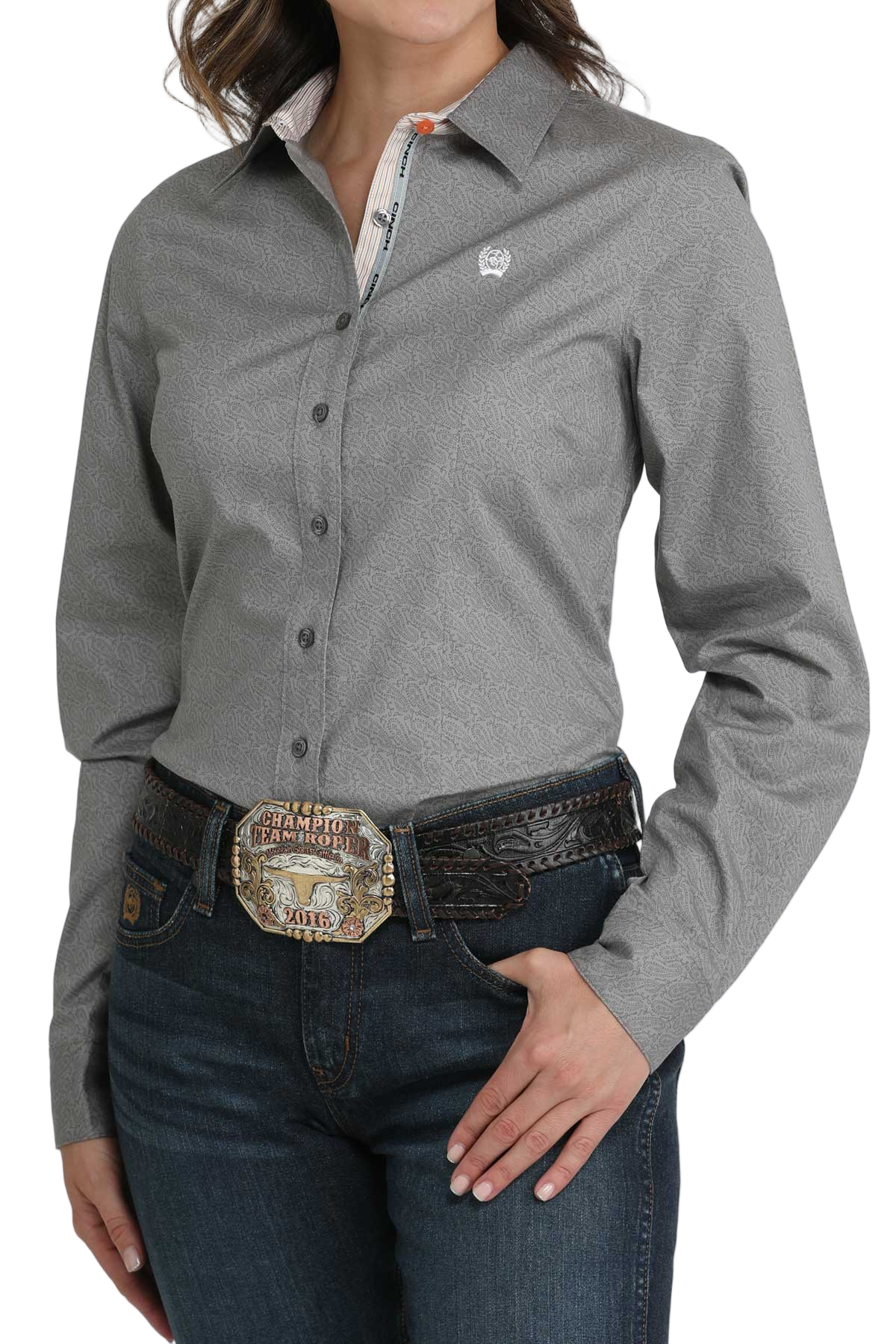 Woman wearing a gray long-sleeve button-down shirt, paired with jeans and a large western belt buckle