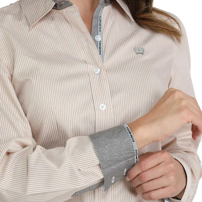 Close-up of a person wearing a striped shirt with rolled-up sleeves, featuring a brand logo.