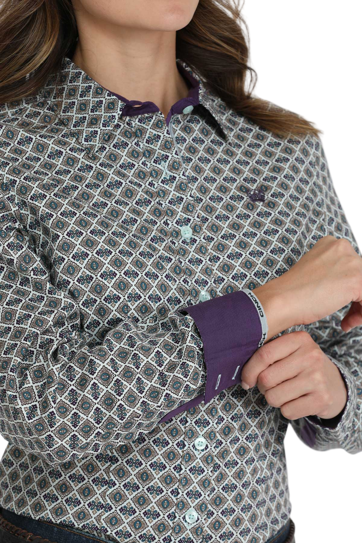 Woman wearing a patterned button-down shirt with purple contrast cuffs and collar trim