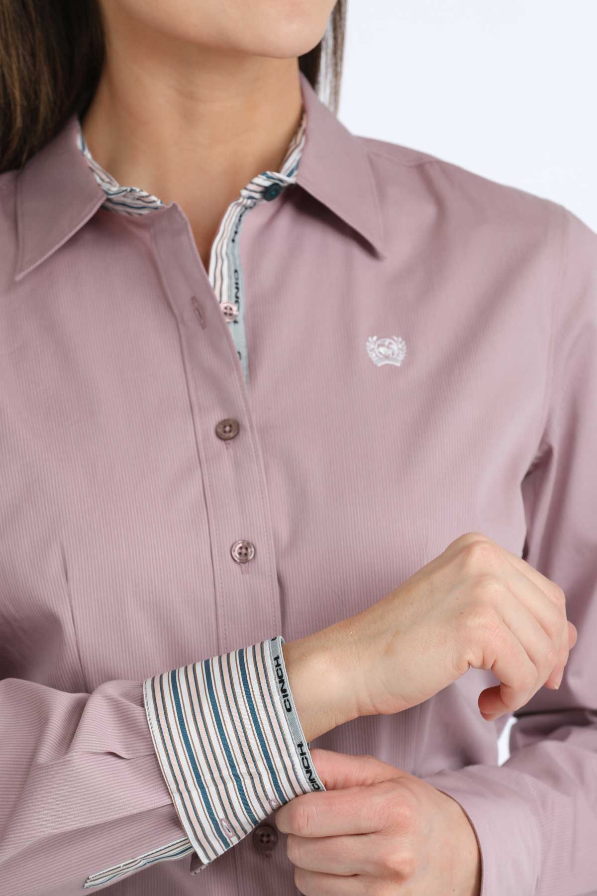 Close-up of a person wearing a pink shirt with rolled-up striped sleeves.