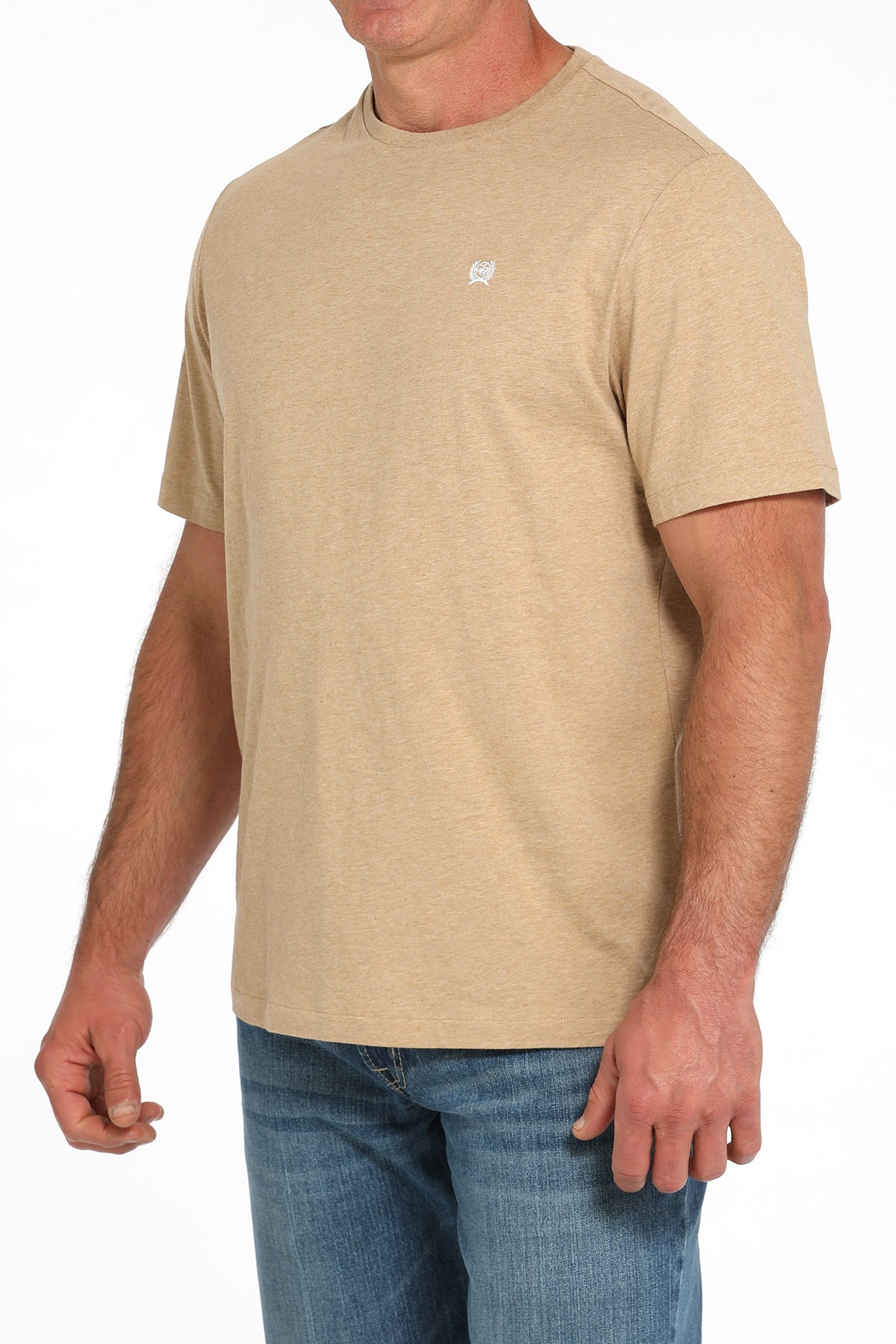 Man wearing a light tan t-shirt and blue jeans on a white background
