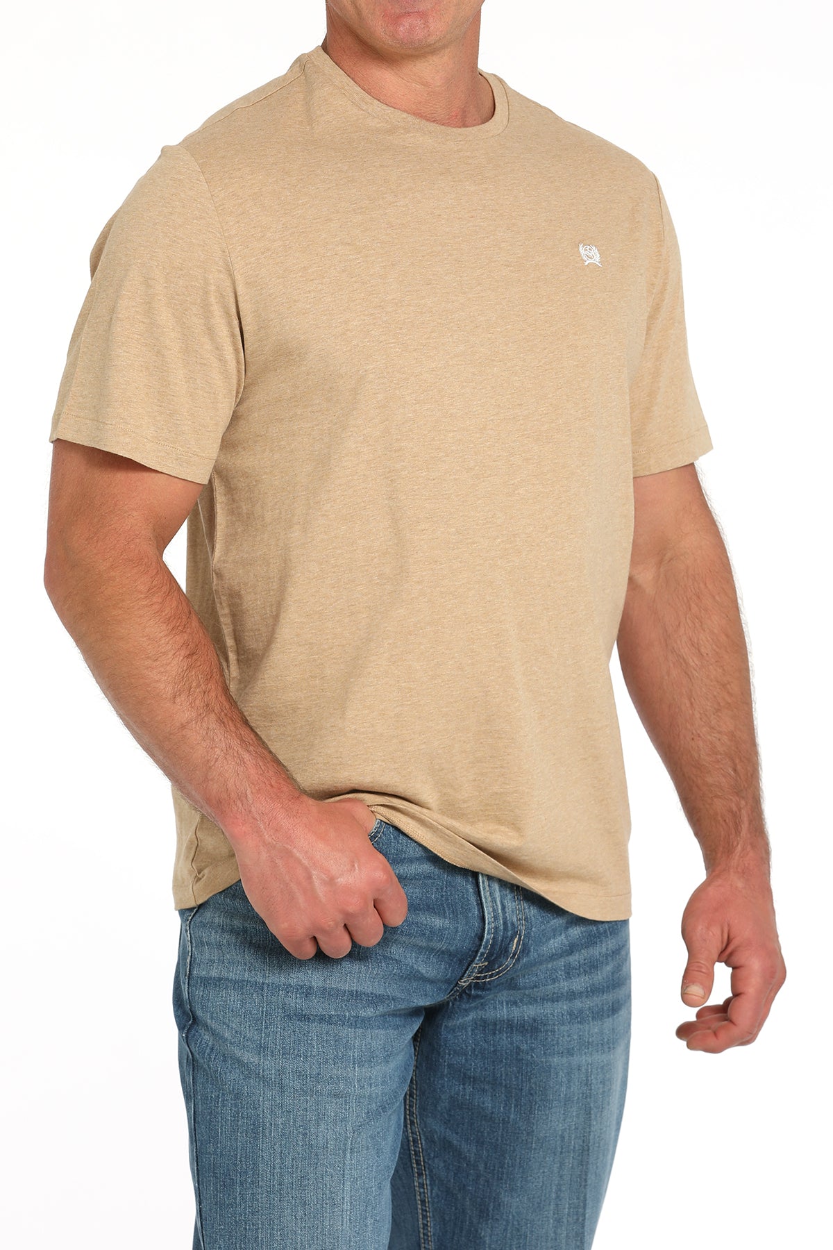 Man wearing a light tan t-shirt and blue jeans on a white background