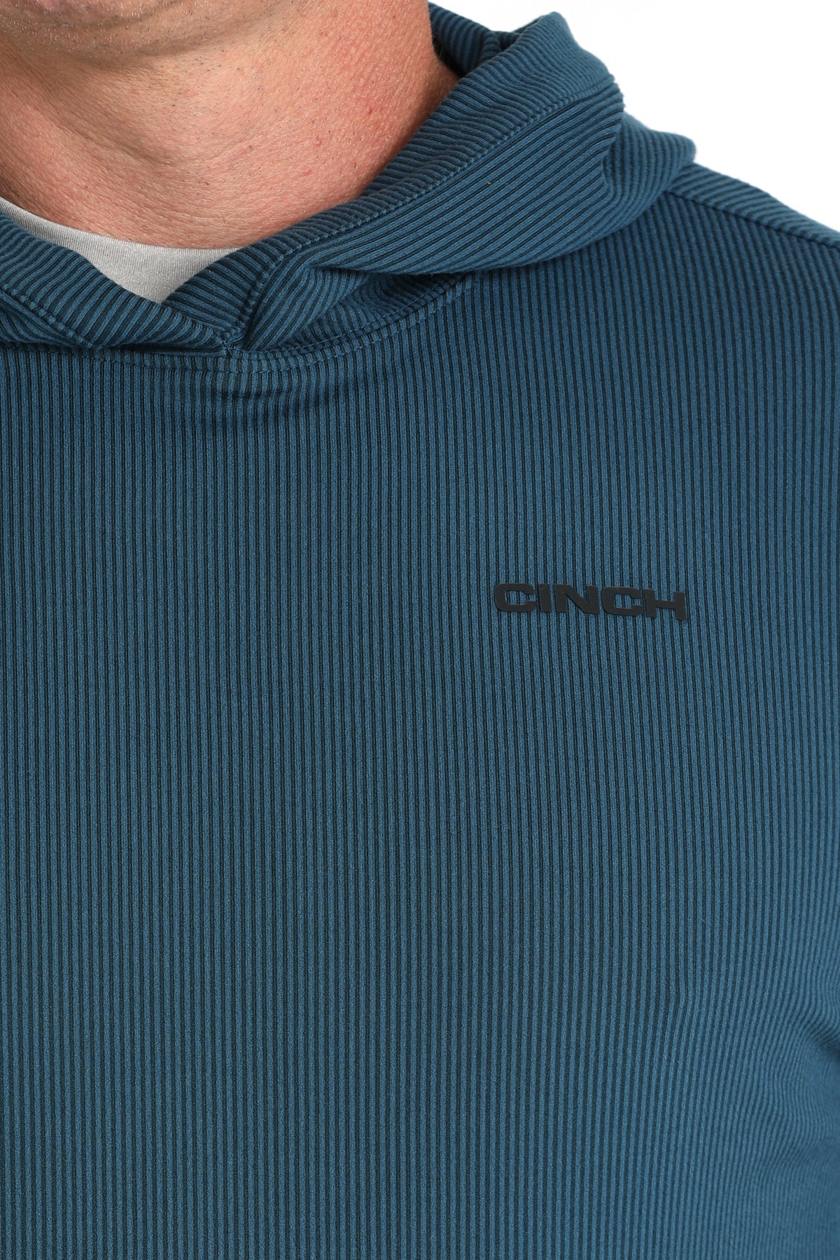 Close-up of a blue ribbed sweater with 'Cinch' logo on a white background